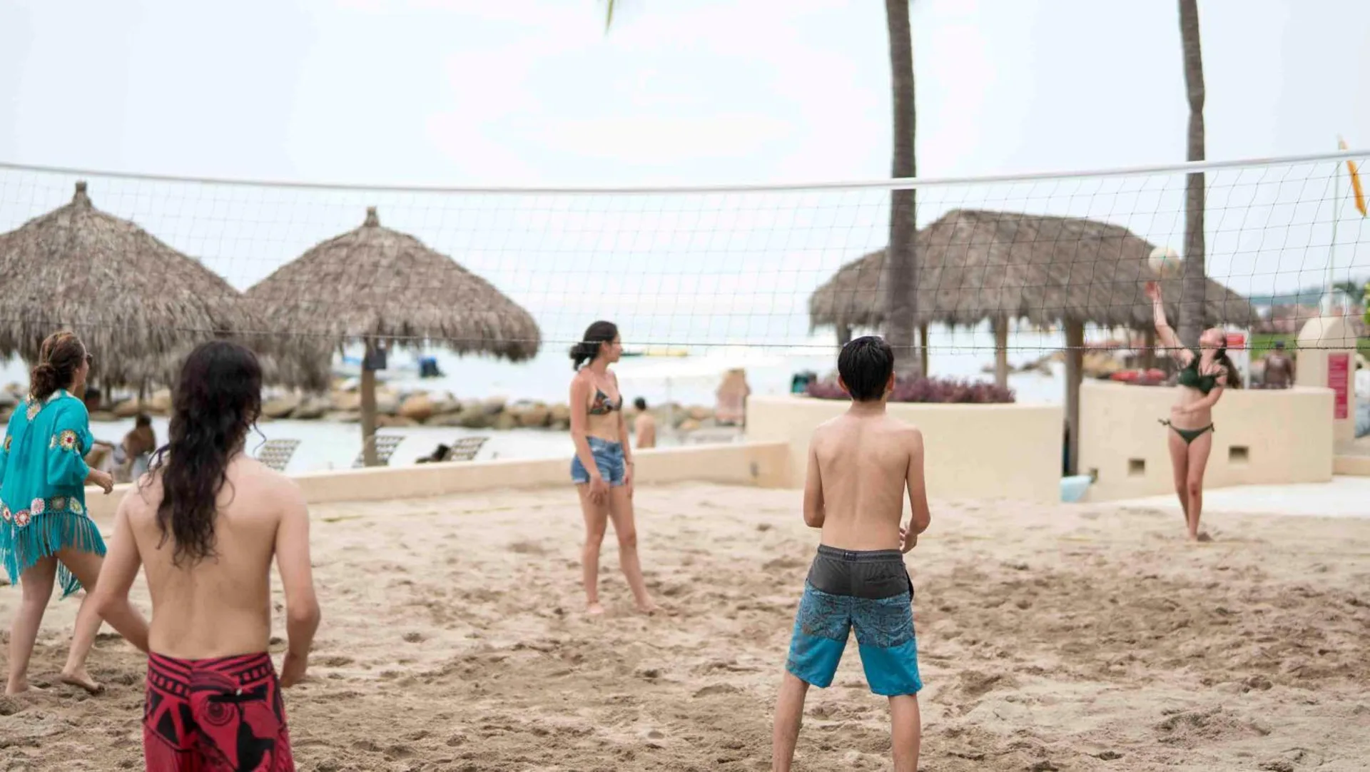 Guests playing beach volleyball near palapas at Club Regina Puerto Vallarta.