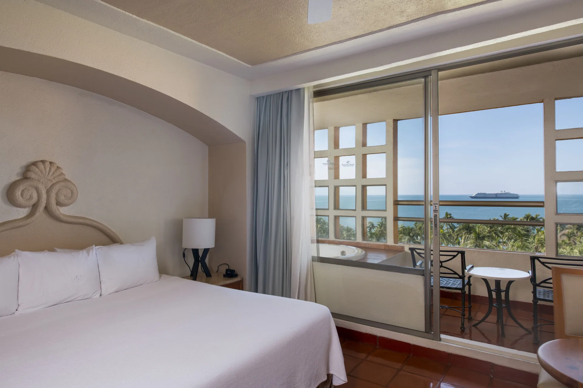 Guest room with king bed and ocean-facing balcony at Club Regina Puerto Vallarta.