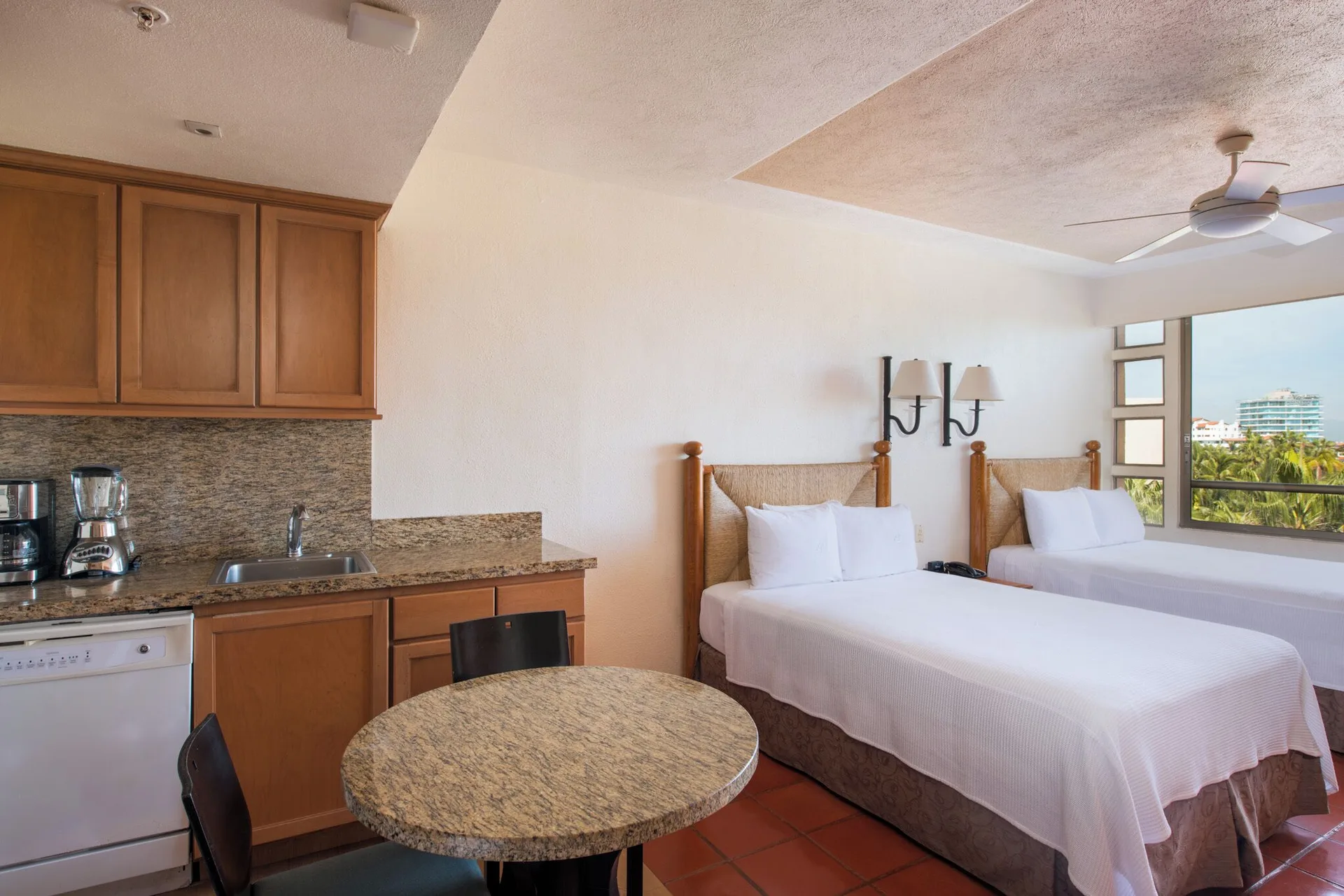 Two-bed guest room with kitchenette and round dining table at Club Regina Puerto Vallarta.