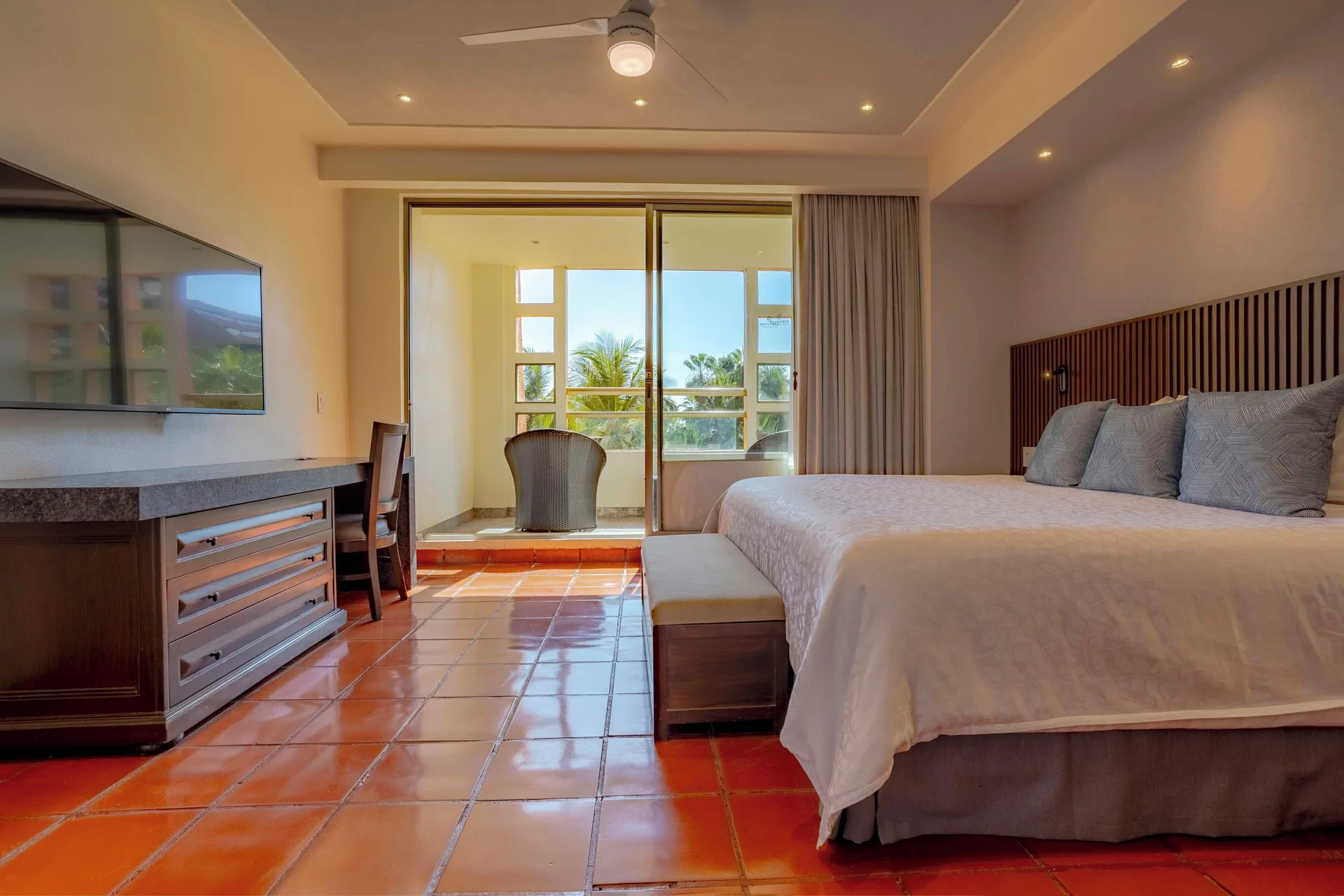 Deluxe suite bedroom with king bed, TV, desk, and balcony at Club Regina Puerto Vallarta.