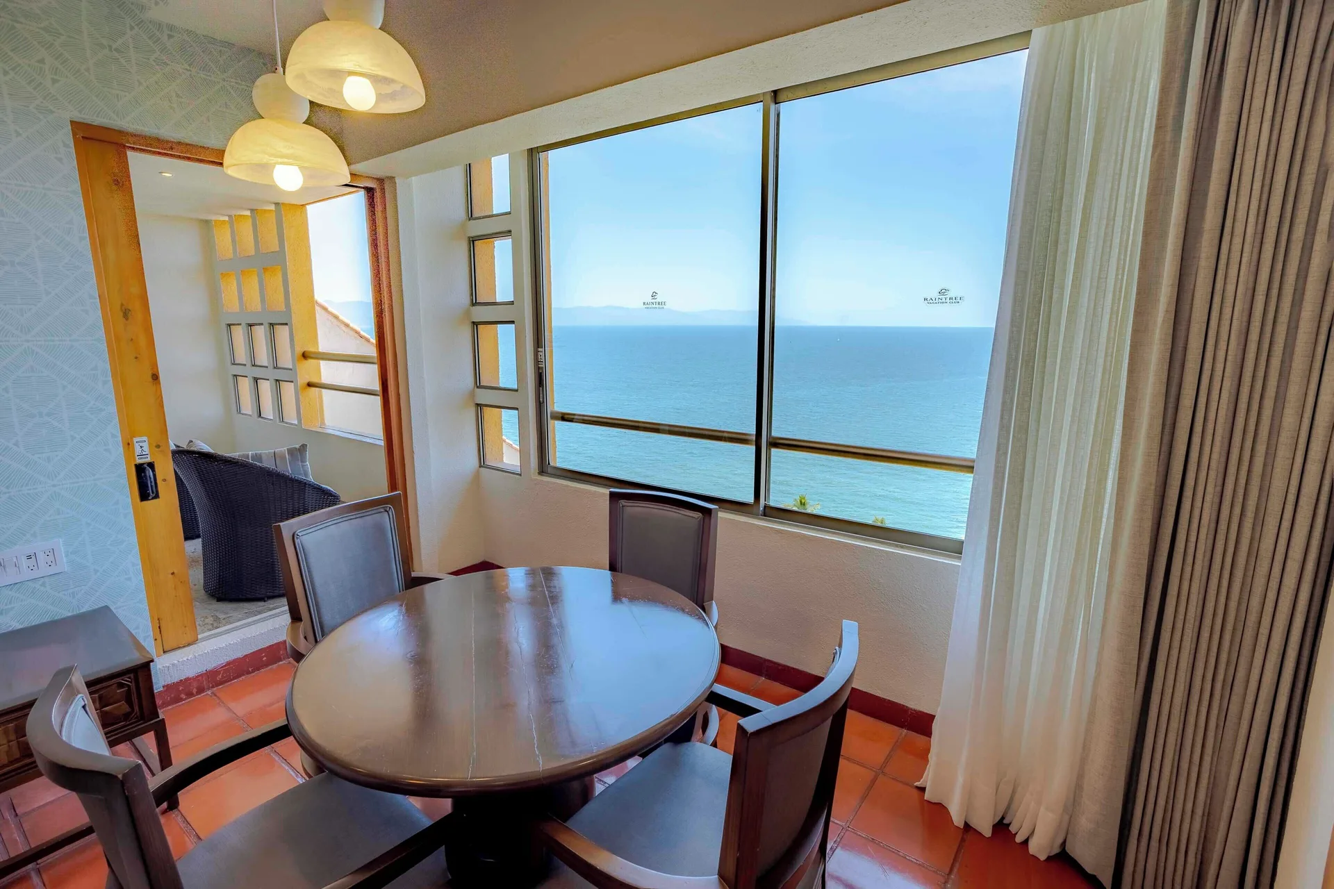 Suite dining table beside large ocean-facing windows and balcony at Club Regina Puerto Vallarta.