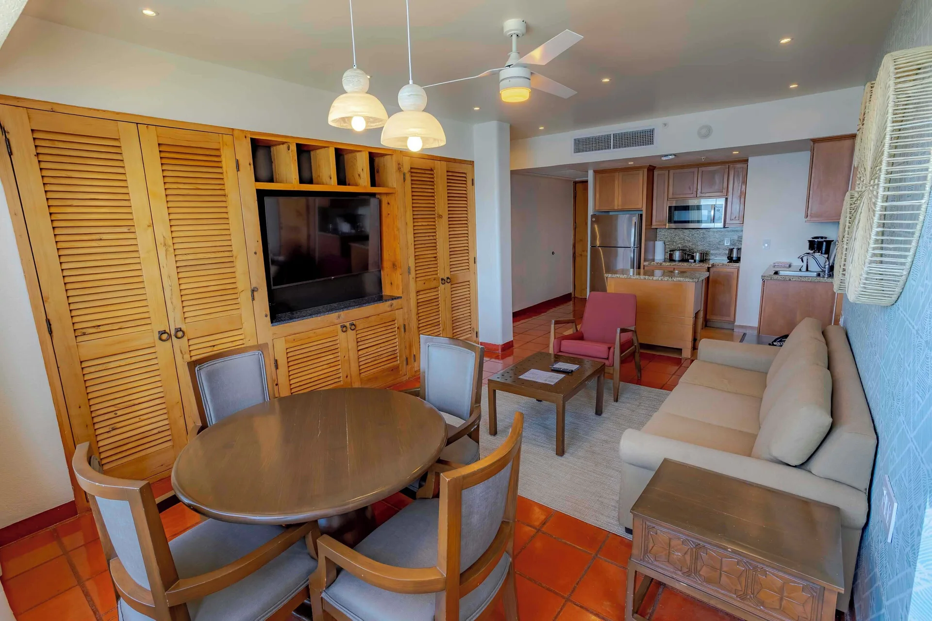 Suite living and dining area with kitchen, sofa, TV cabinet, and round table at Club Regina Puerto Vallarta.