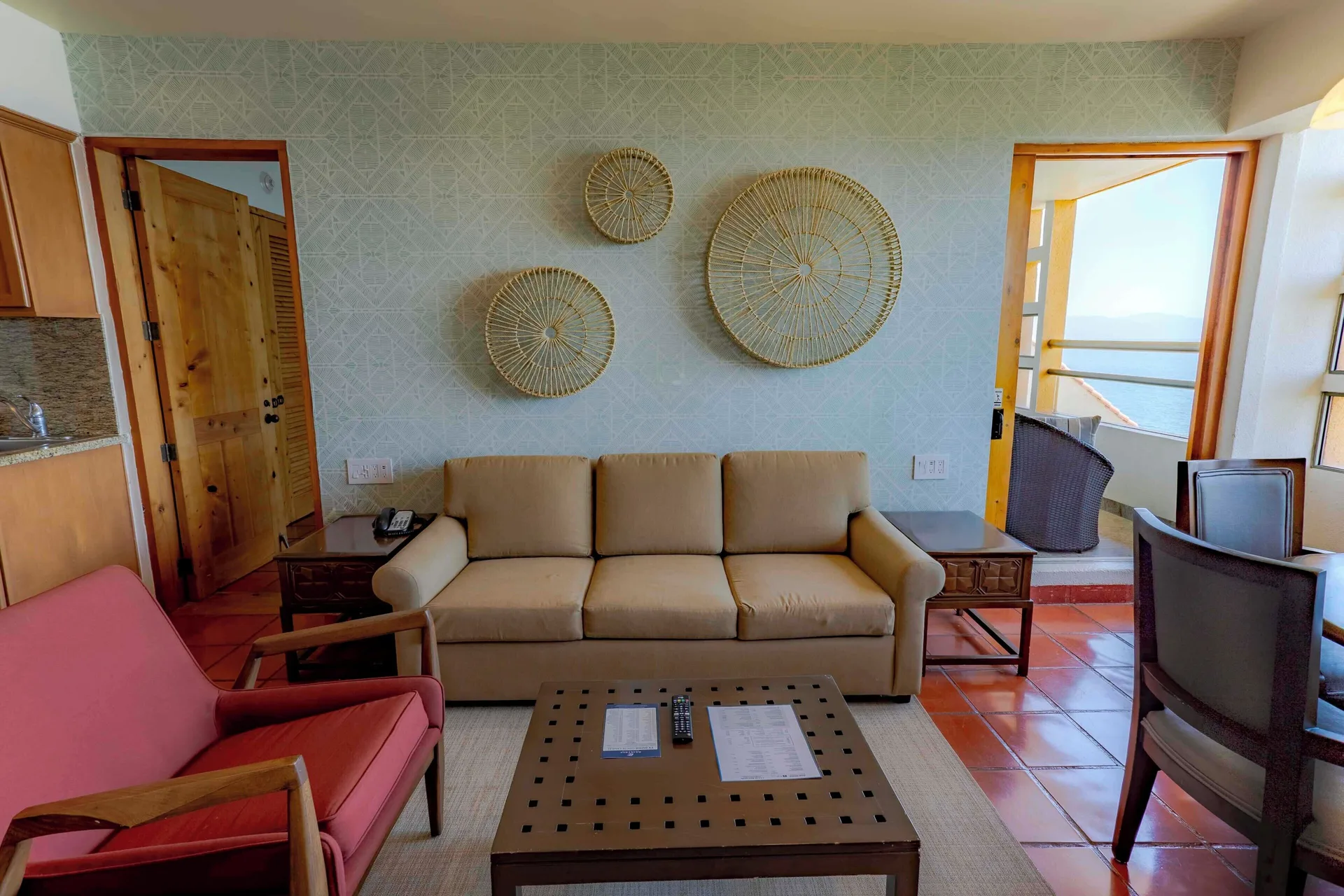 Suite living area with sofa, armchair, coffee table, and balcony doorway at Club Regina Puerto Vallarta.