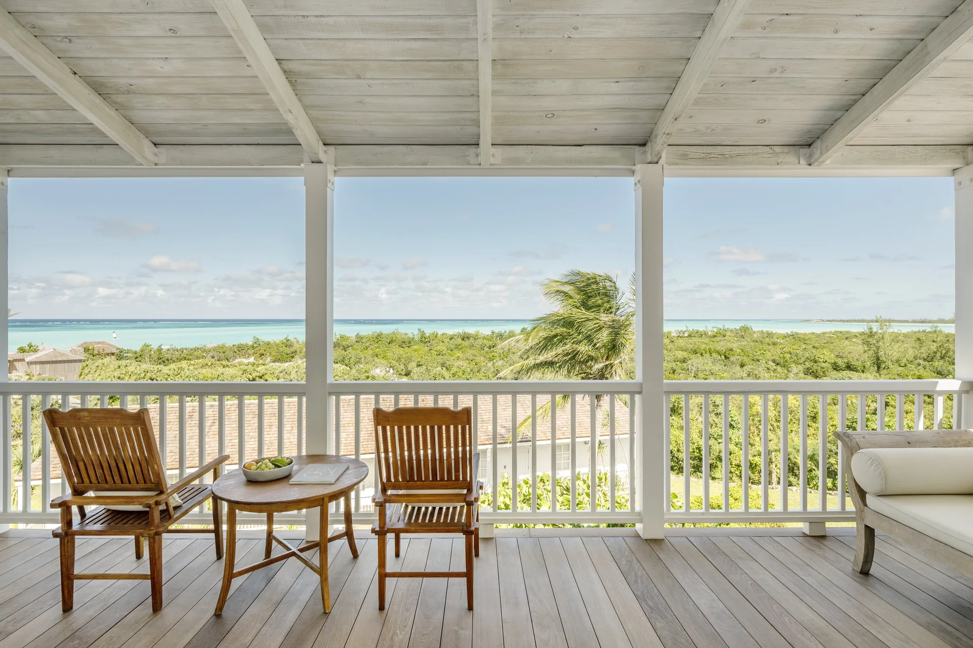 Covered veranda with wooden chairs and ocean views at COMO Parrot Cay.