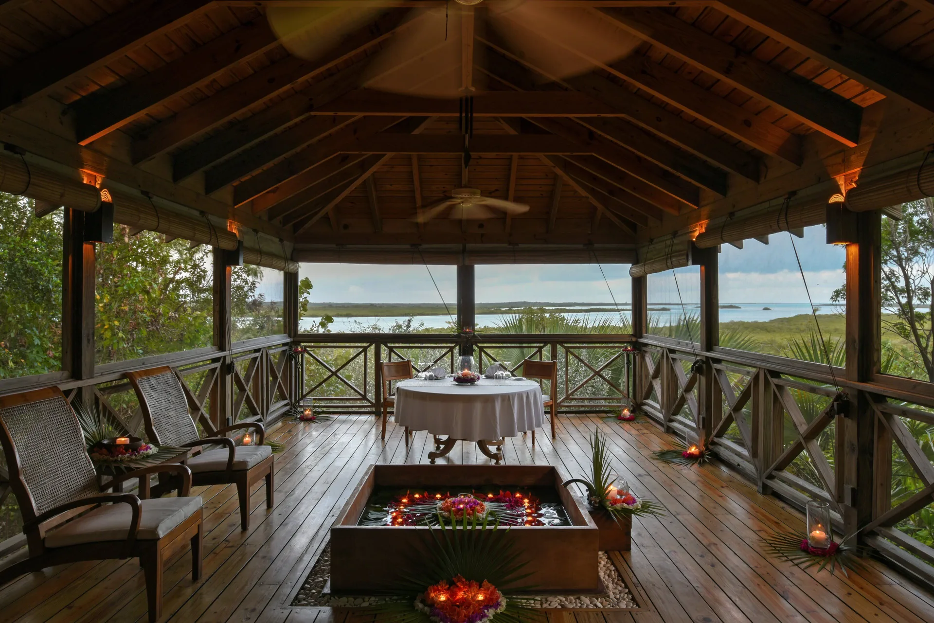 Open-air spa pavilion at COMO Parrot Cay with candles, flowers, seating, and water views.