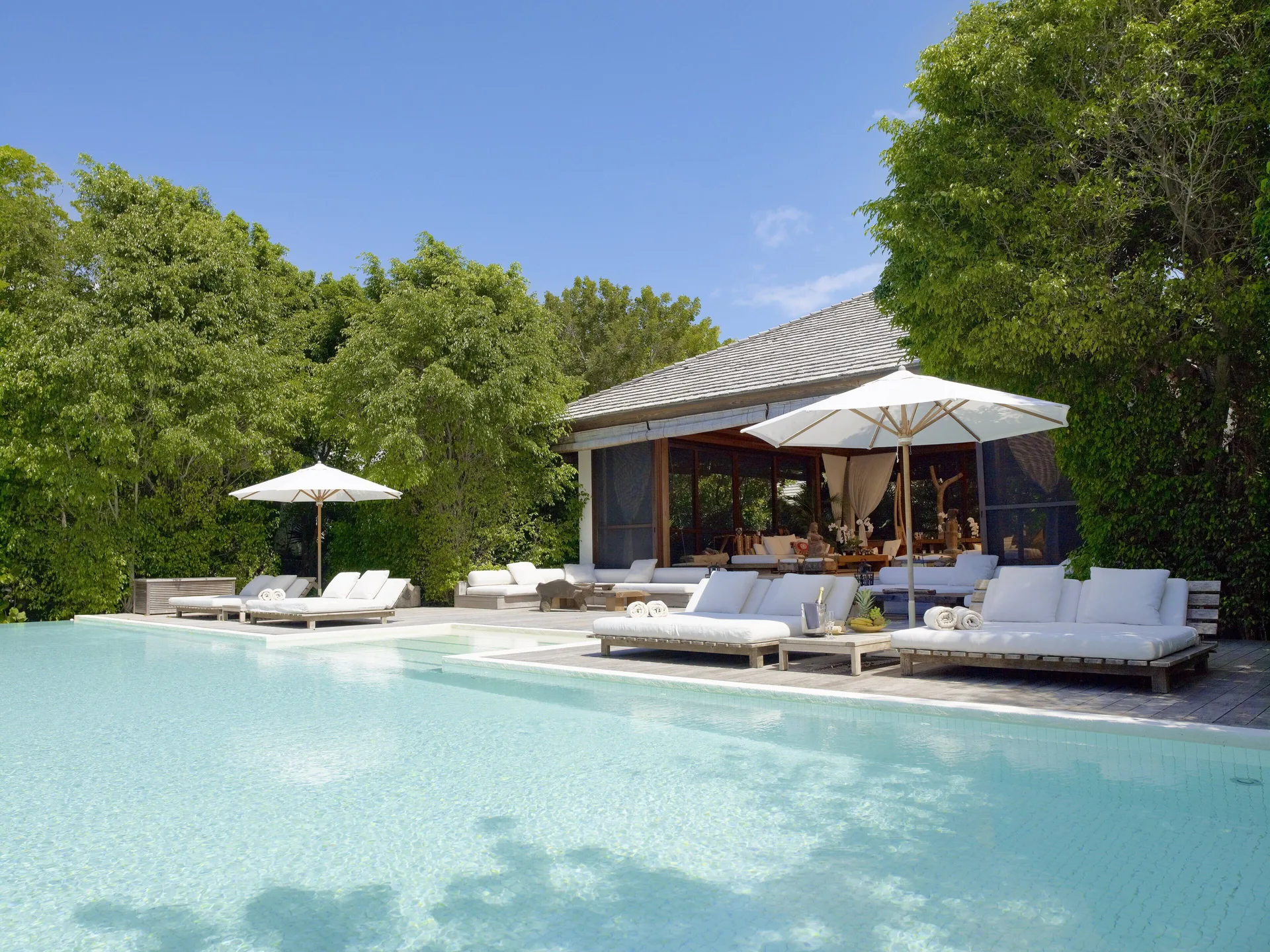 Resort pool with loungers and umbrellas beside a villa at COMO Parrot Cay.
