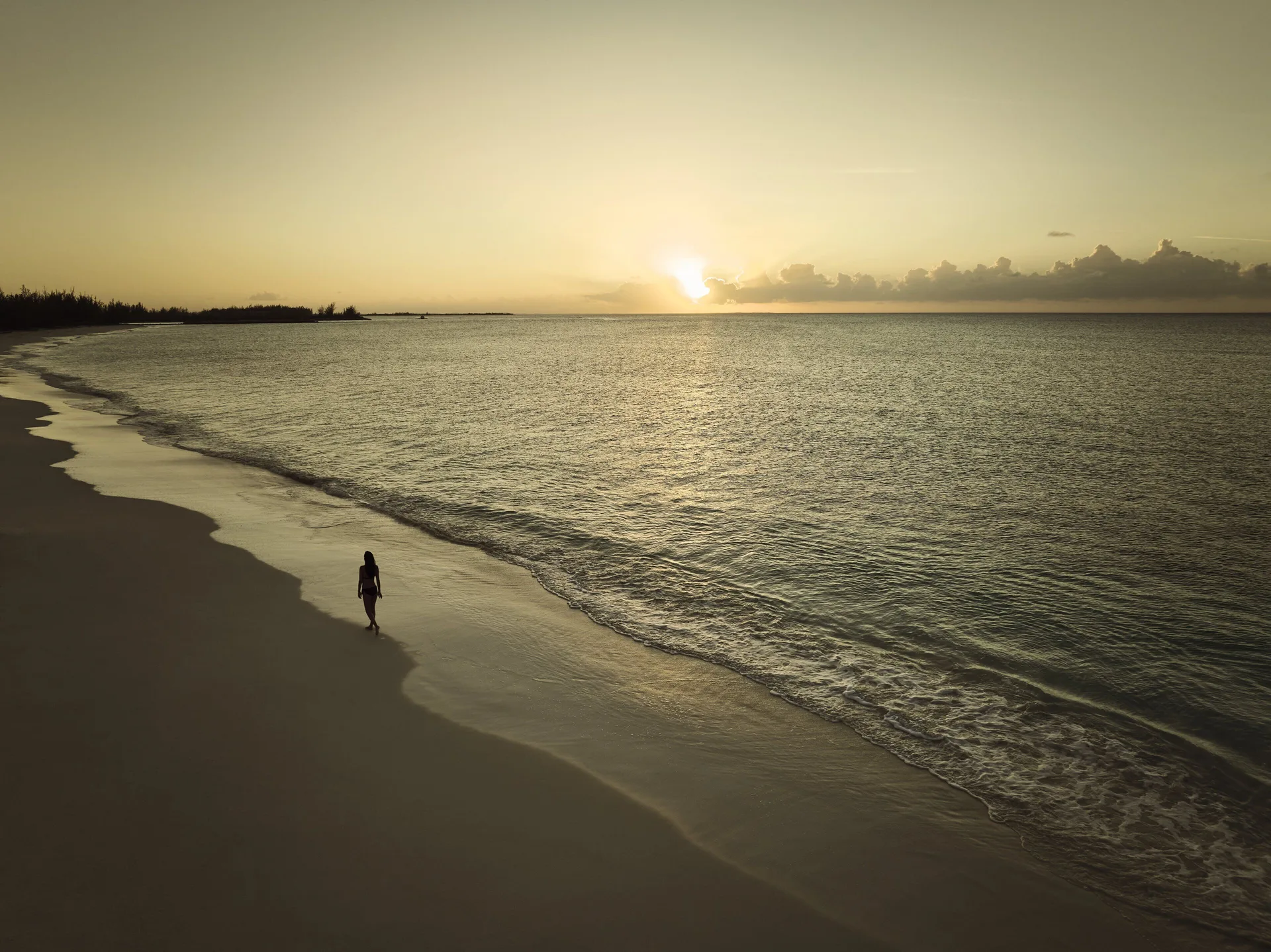 A lone walker follows the shoreline at sunset at COMO Parrot Cay.