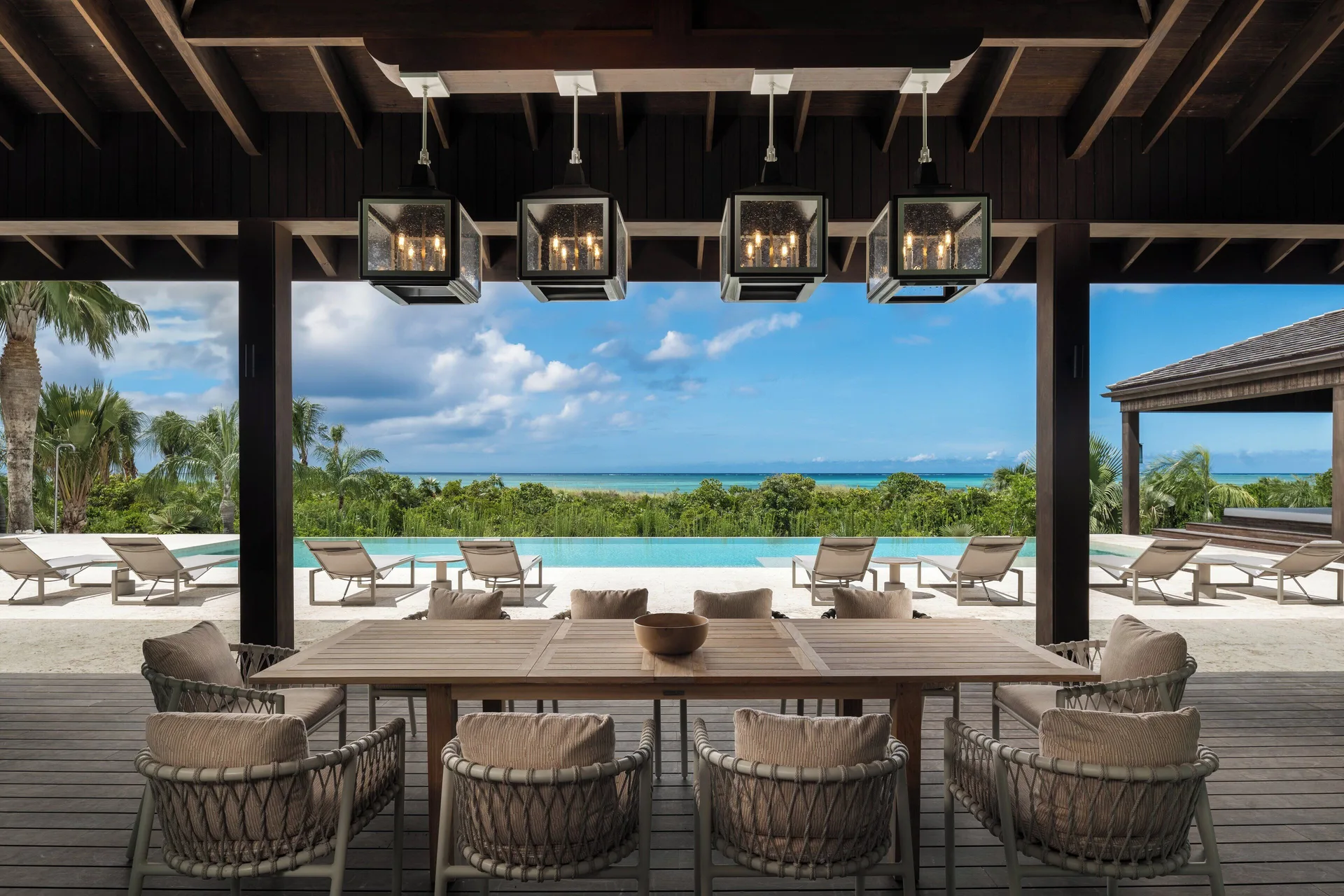 Covered outdoor dining terrace at COMO Parrot Cay overlooking an infinity pool and ocean.