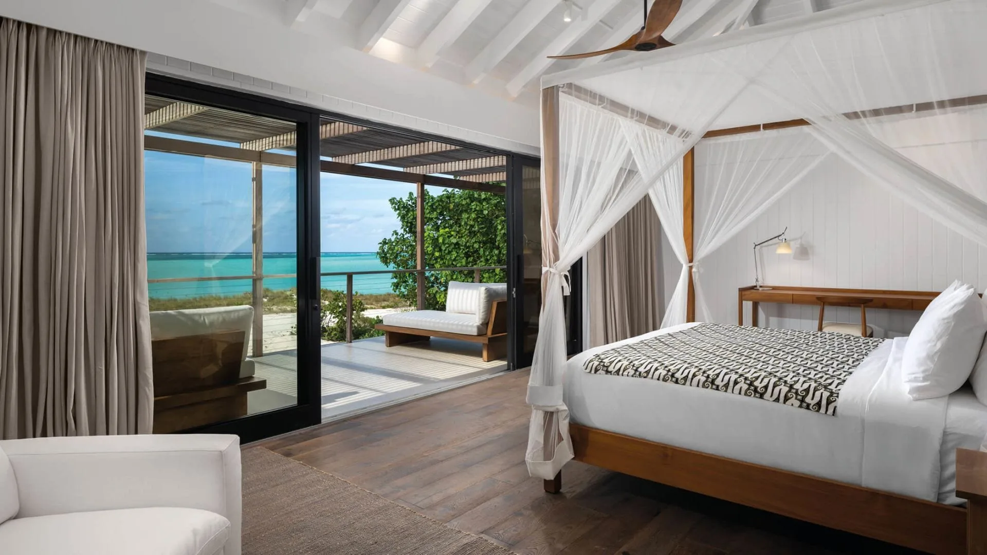 Como Villa bedroom with canopy bed and ocean-facing terrace at COMO Parrot Cay.