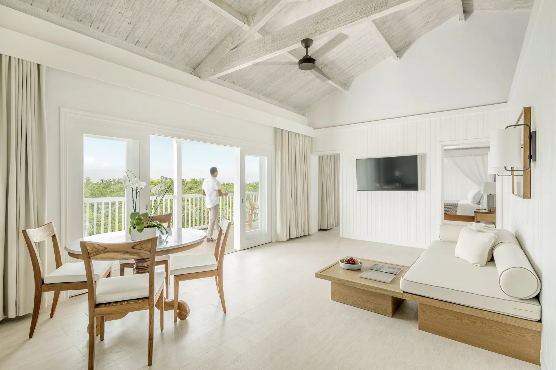 COMO Parrot Cay living room with dining table, daybed and balcony doors at COMO Parrot Cay.
