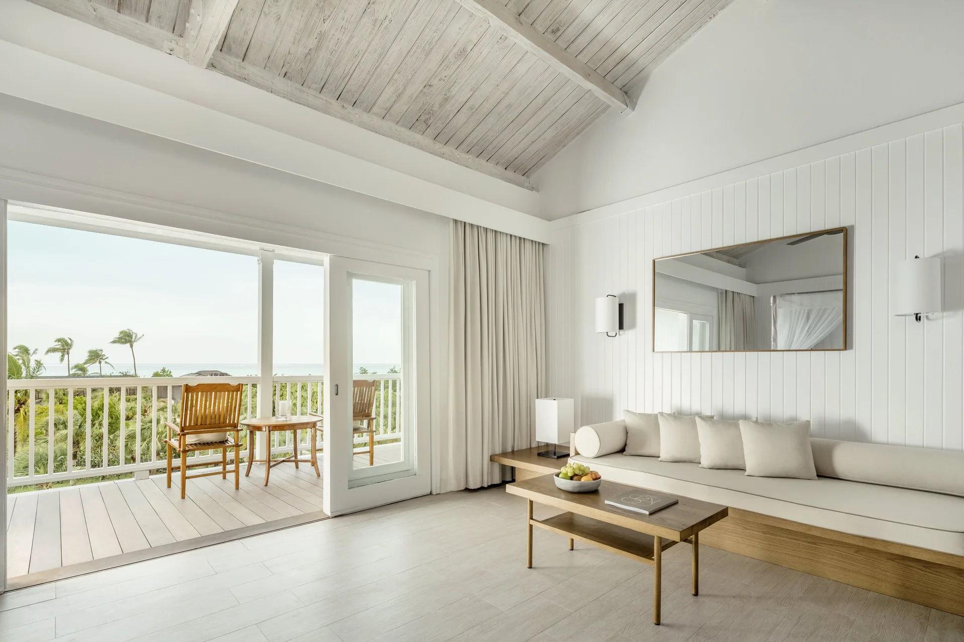 Terrace Room sitting area and balcony at COMO Parrot Cay with white sofa and ocean glimpses.