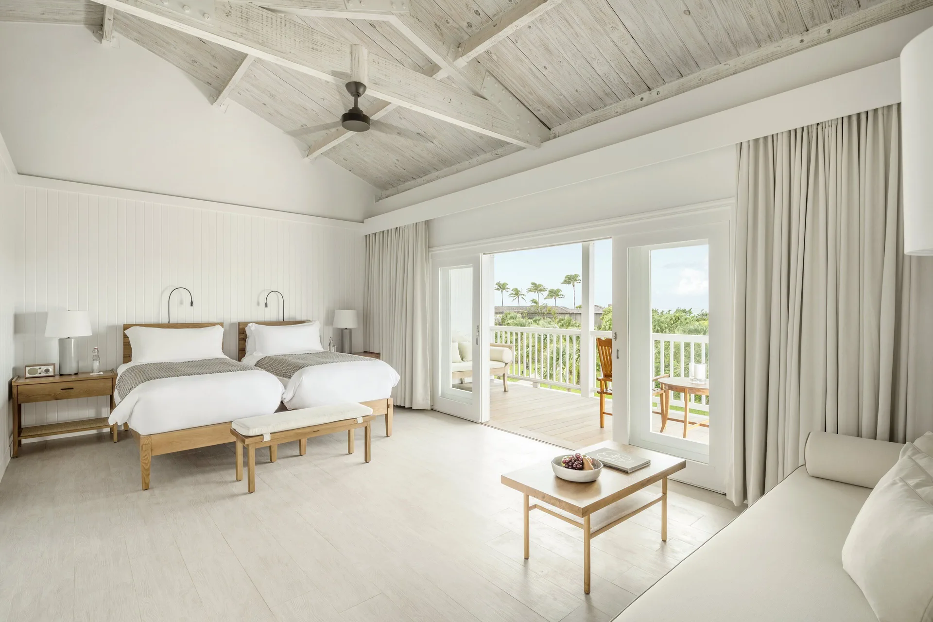 Terrace Room twin beds at COMO Parrot Cay with balcony doors and a pale wood ceiling.