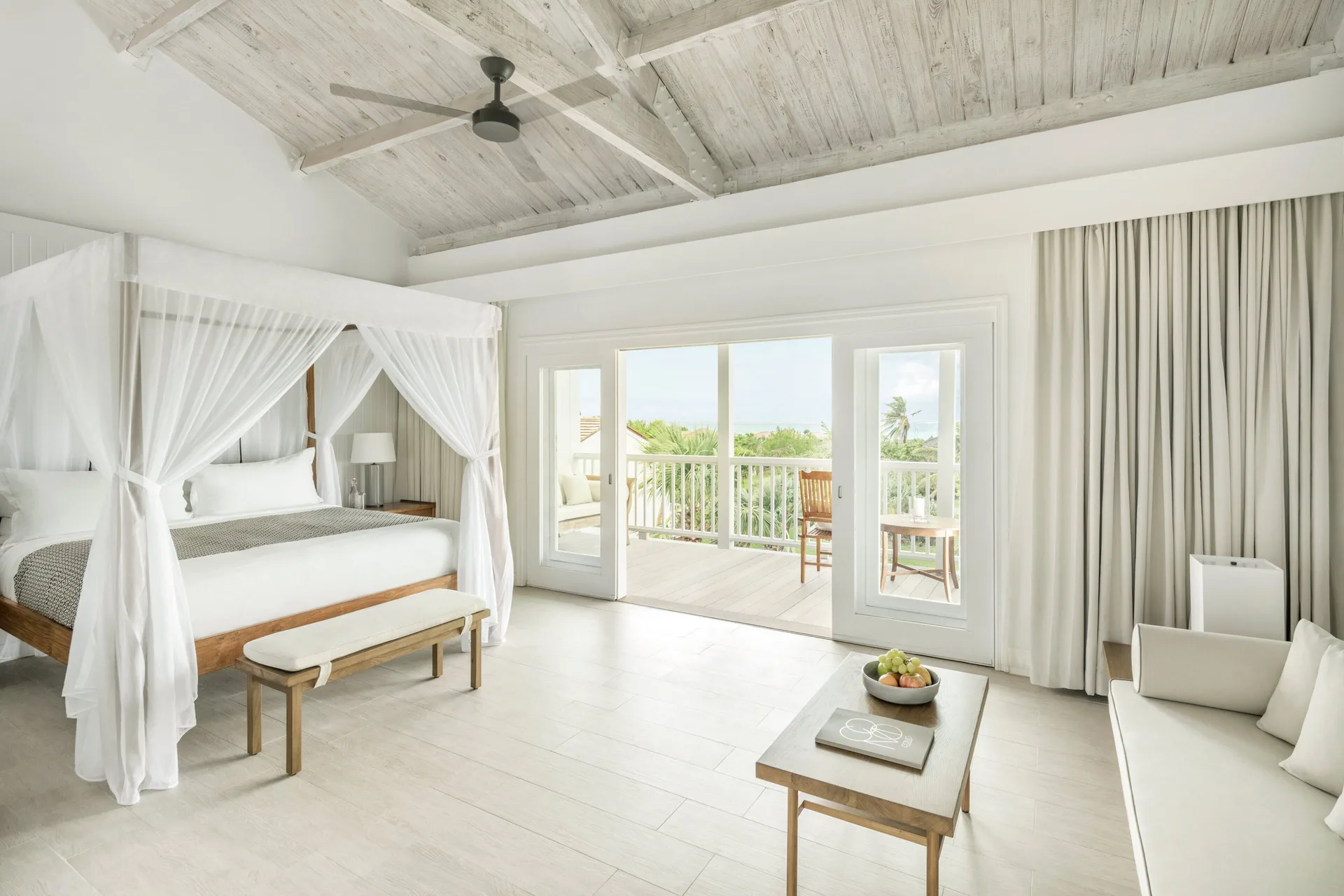 Terrace Room at COMO Parrot Cay with canopy bed, vaulted ceiling, sofa, and balcony.