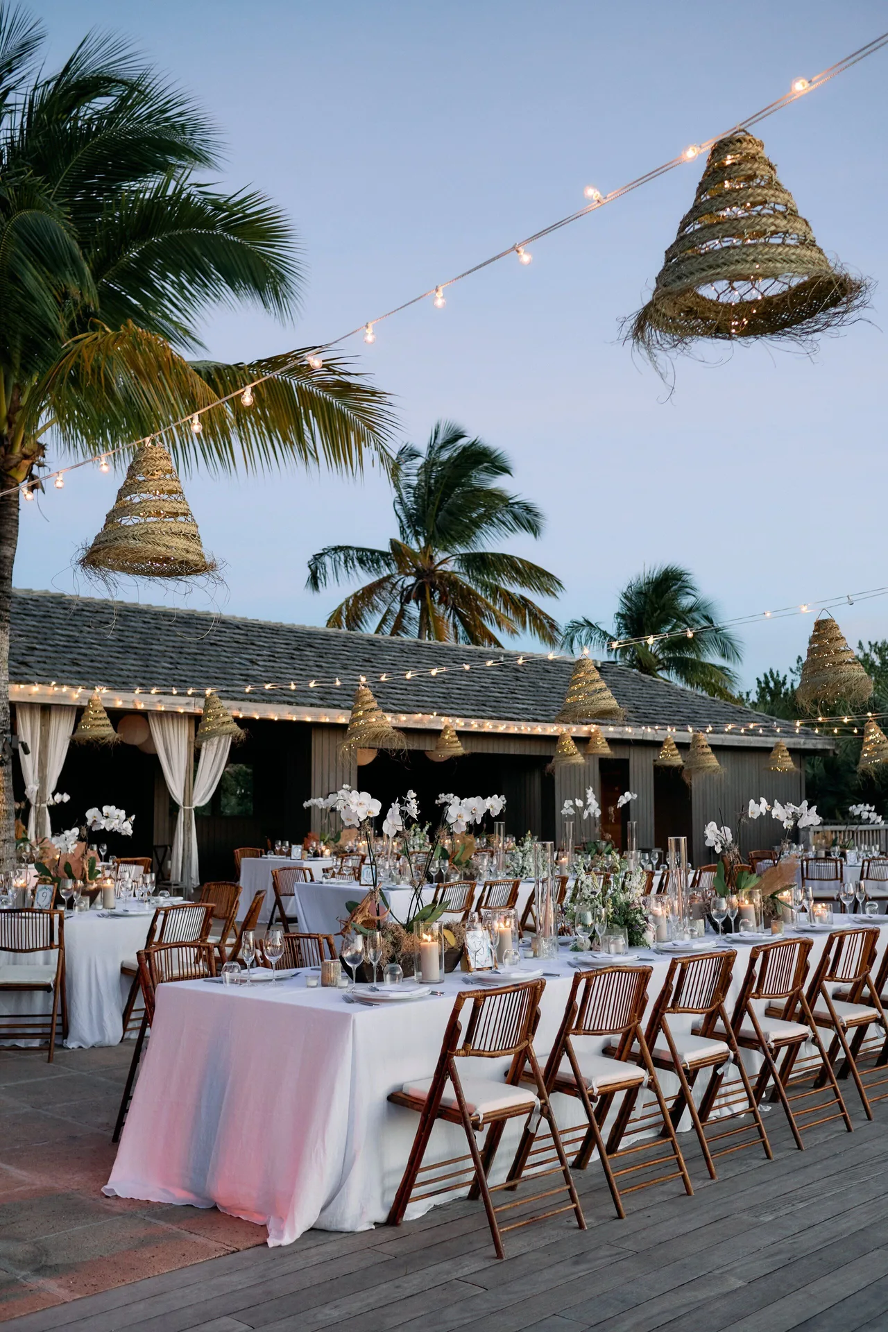An outdoor event dinner with long tables and hanging lights at COMO Parrot Cay.