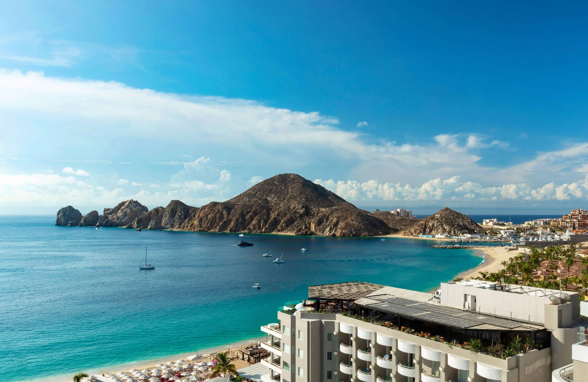 Turquoise bay, beach, boats, and rocky headlands beside Corazón Cabo.