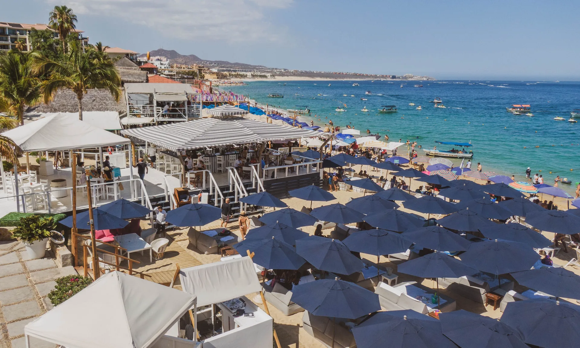 Beach club umbrellas and waterfront seating along the shore at Corazón Cabo.