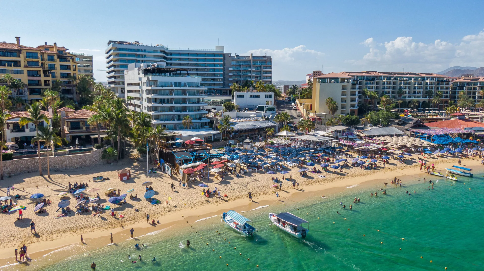 Aerial view of beach umbrellas, boats, and resort buildings at Corazón Cabo.