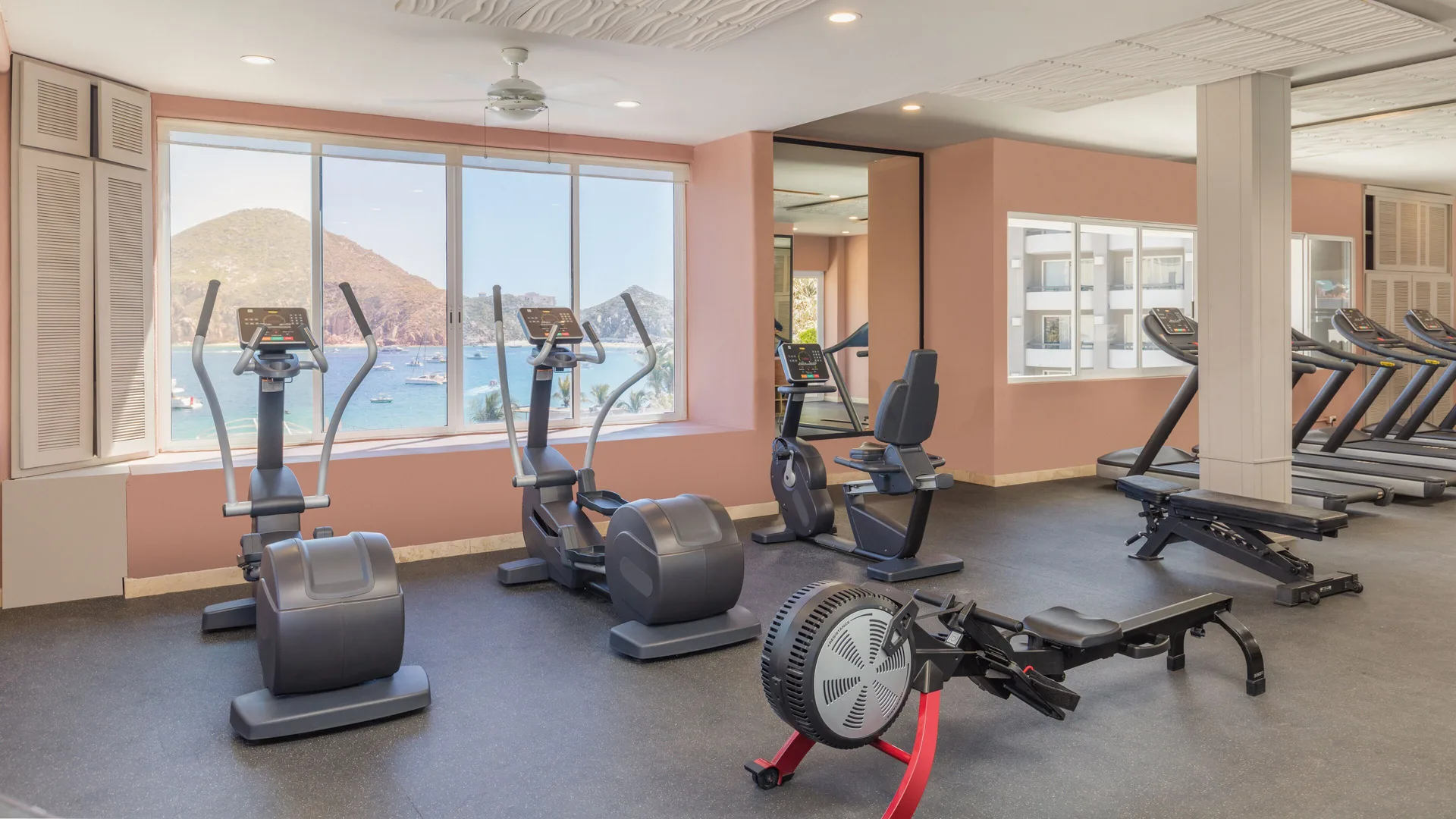 Fitness center with cardio machines and bay-facing windows at Corazón Cabo.