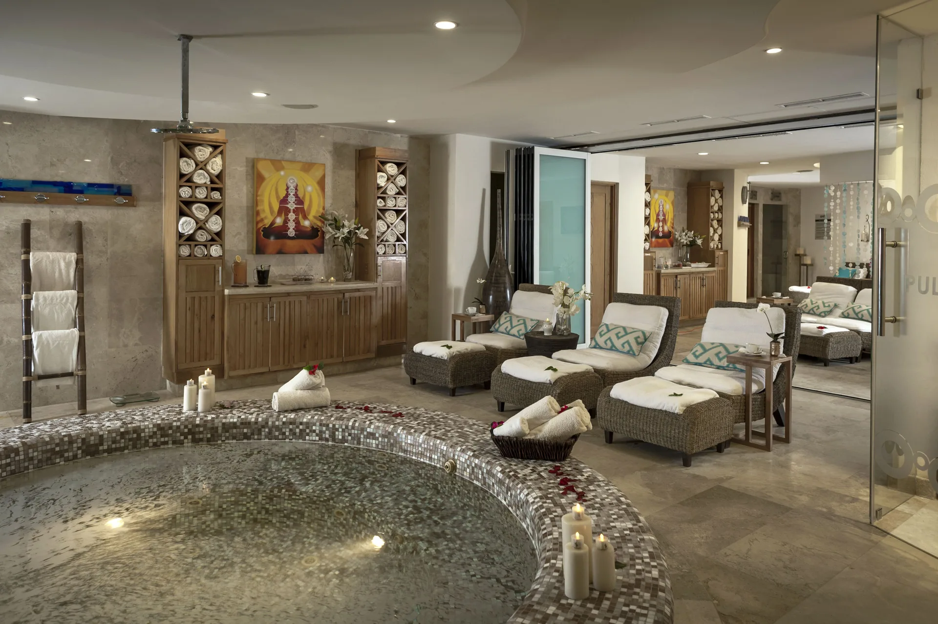 Spa relaxation room with tiled pool, loungers, candles, and towels at Corazón Cabo.