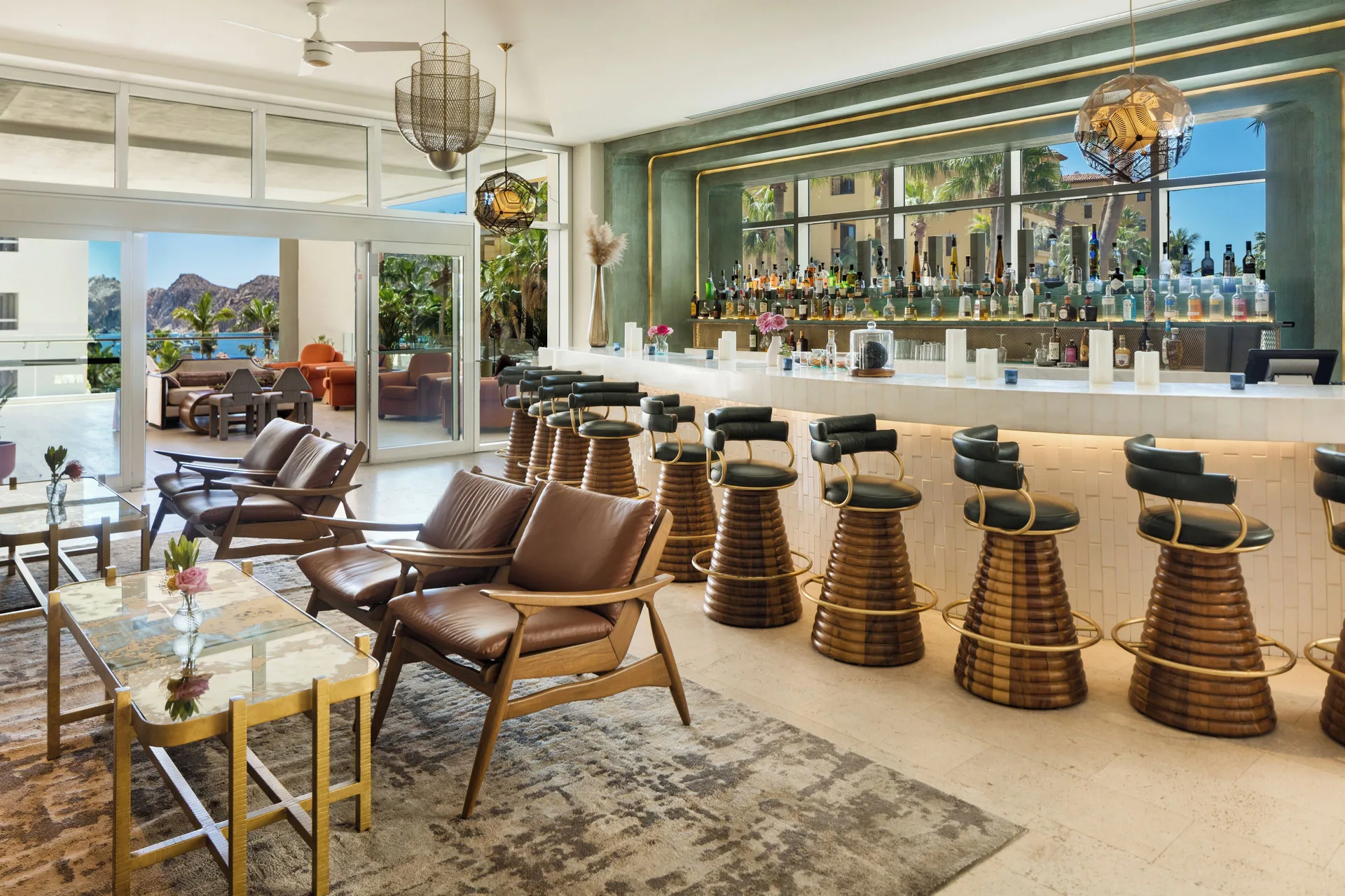 Bright bar lounge with stools, leather chairs and ocean glimpses at Corazón Cabo.