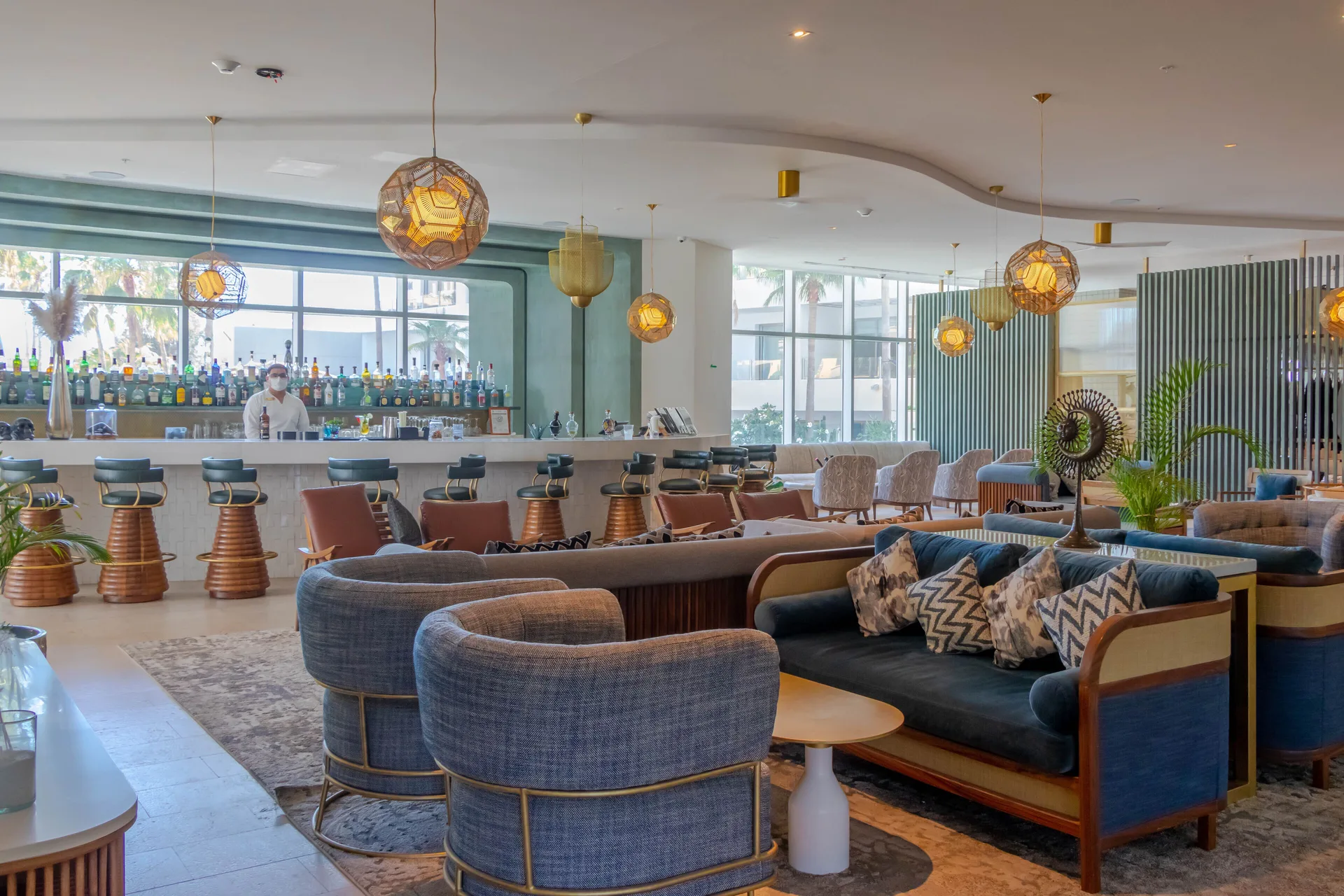 Lobby lounge bar with sofas, pendant lights, and counter seating at Corazón Cabo.