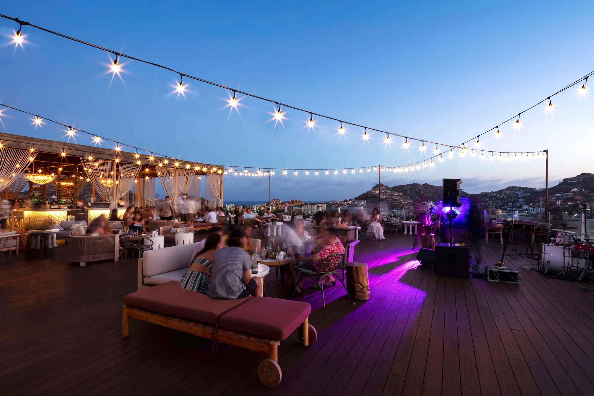 Evening rooftop gathering at Corazón Cabo with string lights, guests, and live music setup.