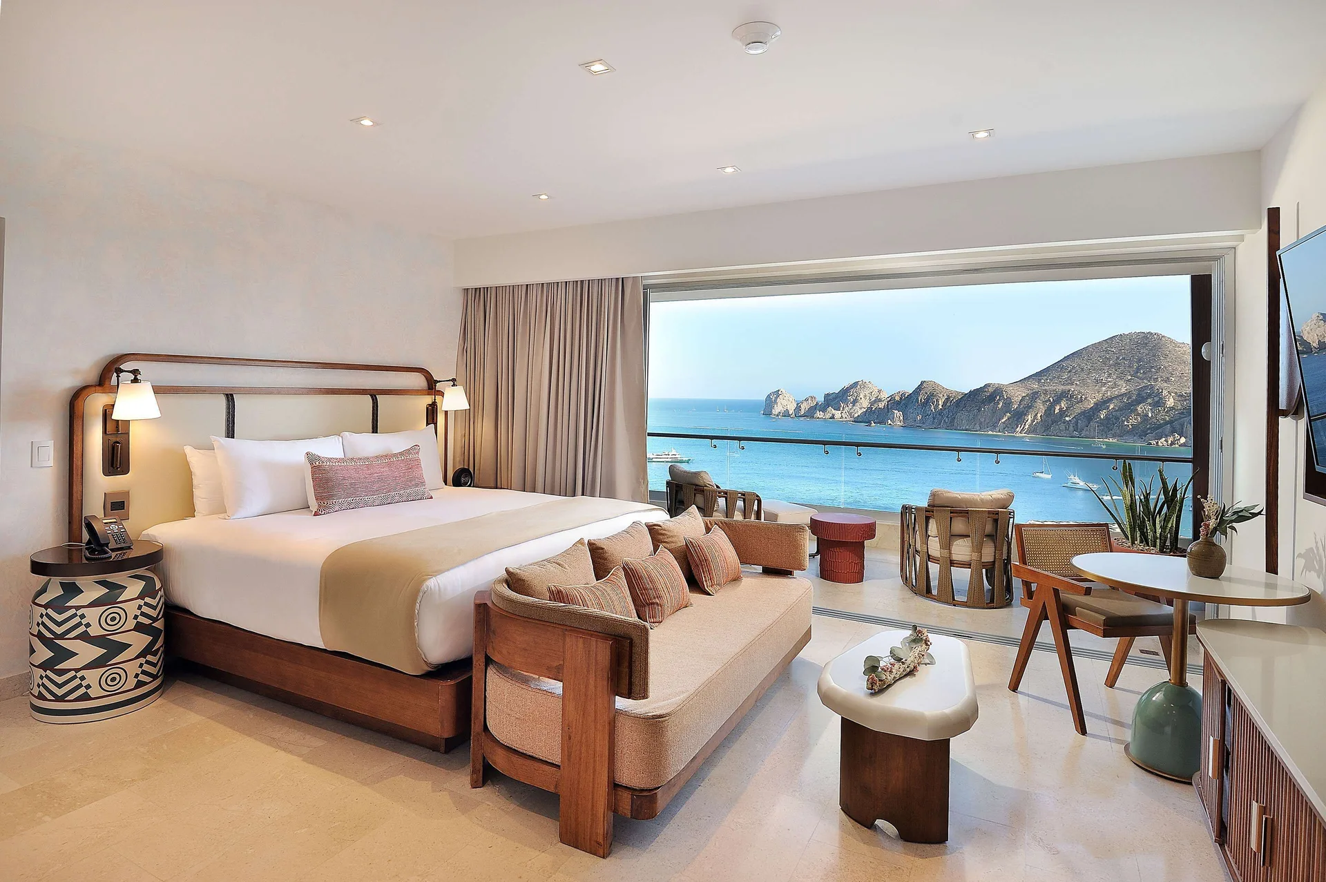 Infinity Ocean View king bed, sofa, desk, and ocean-facing balcony at Corazón Cabo.