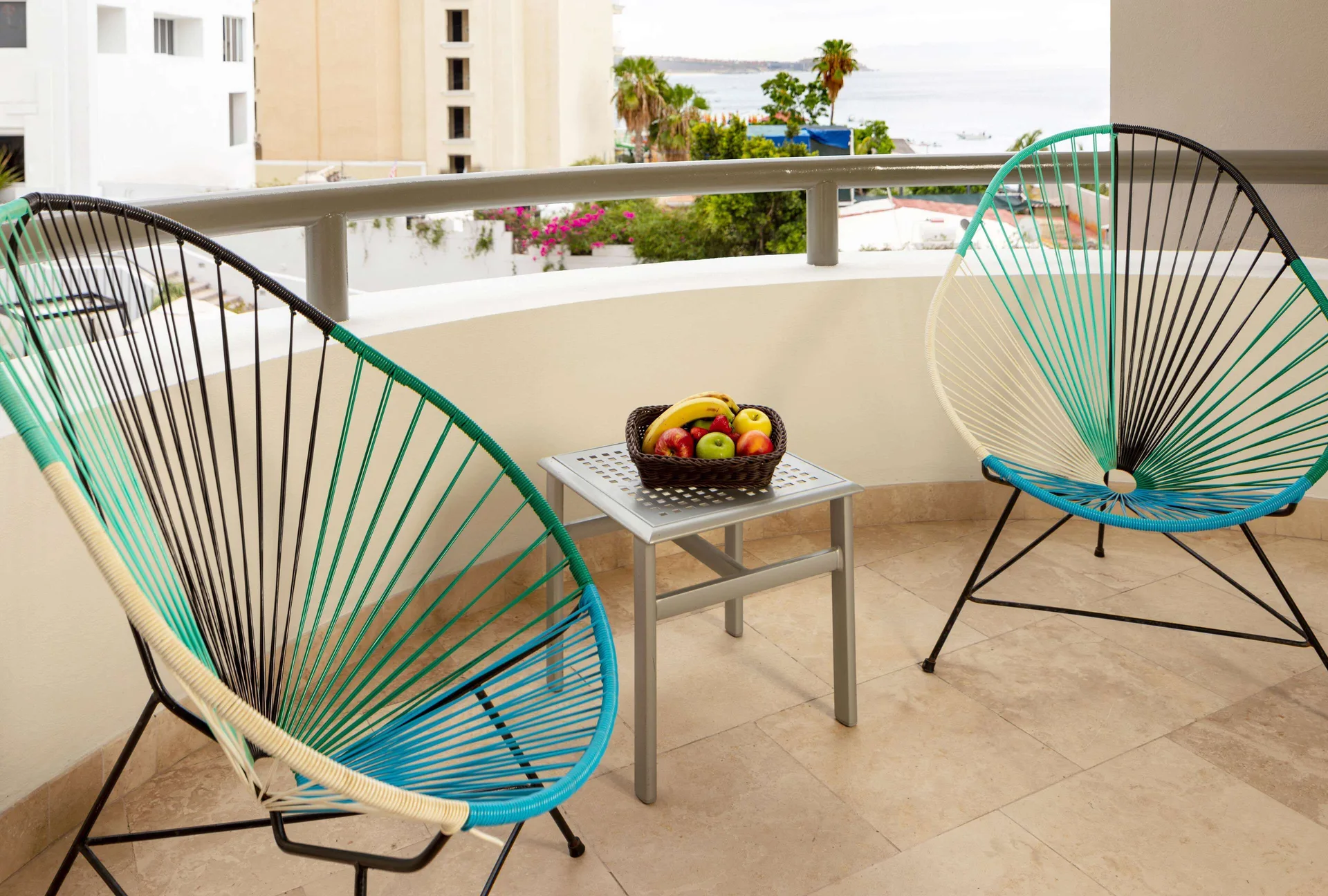 One Bedroom Deluxe balcony with two lounge chairs and a partial ocean view at Corazón Cabo.