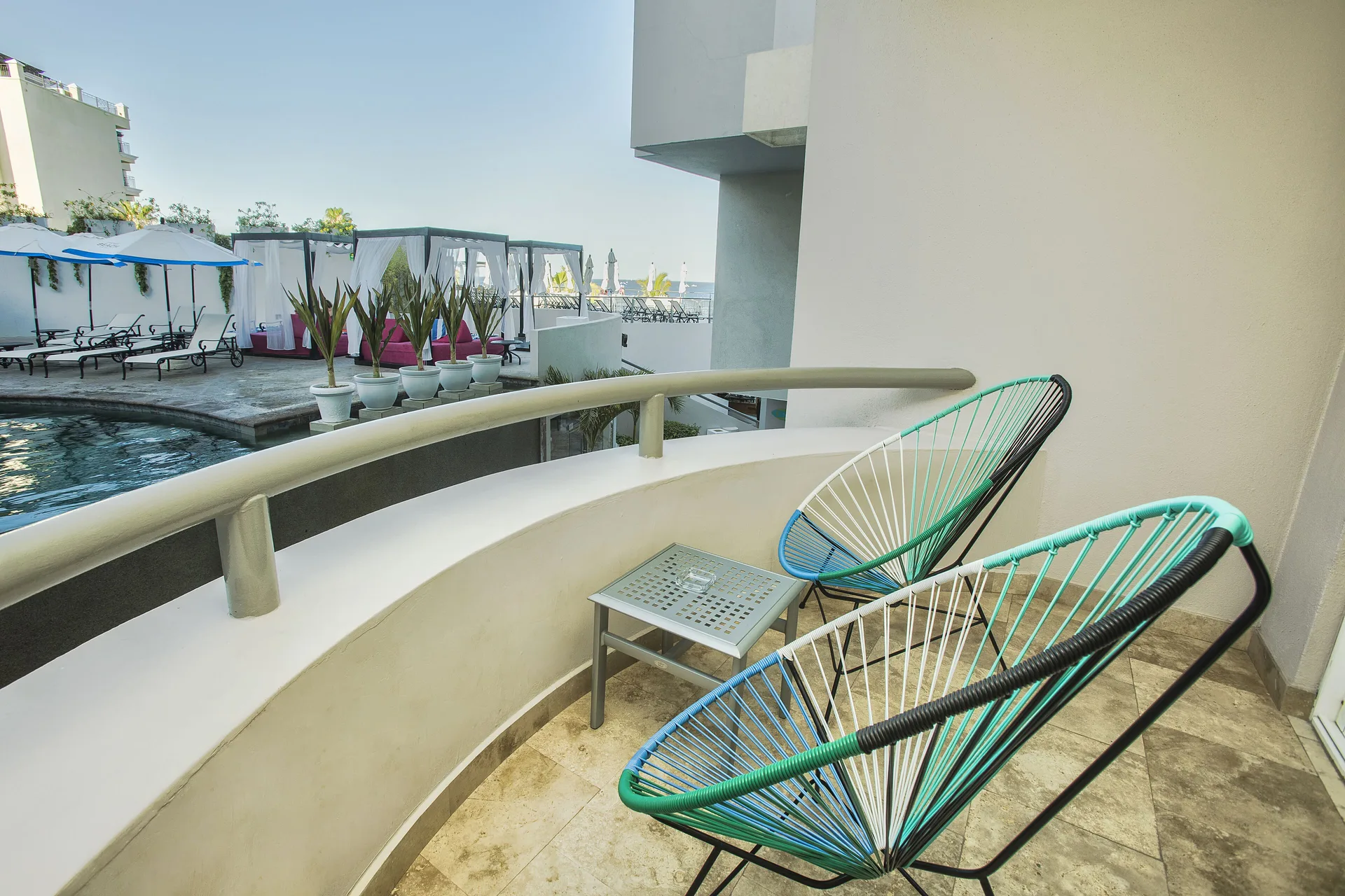 One Bedroom Deluxe balcony with two chairs overlooking the pool at Corazón Cabo.