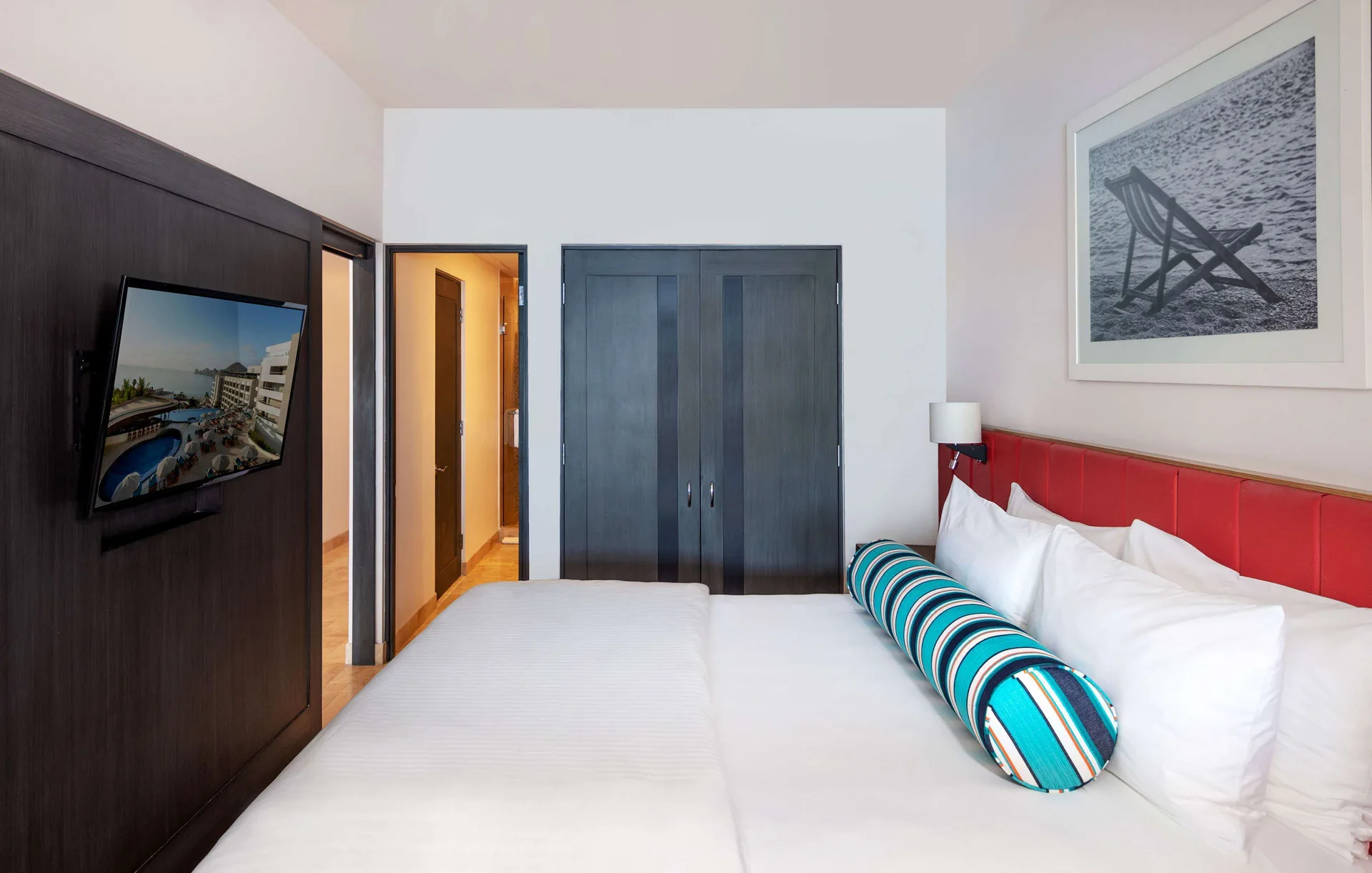 One Bedroom Deluxe king bed, TV, and wardrobe at Corazón Cabo.