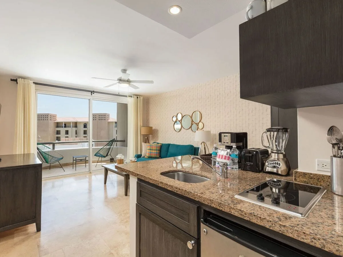 One Bedroom Deluxe kitchenette and living area opening to the balcony at Corazón Cabo.