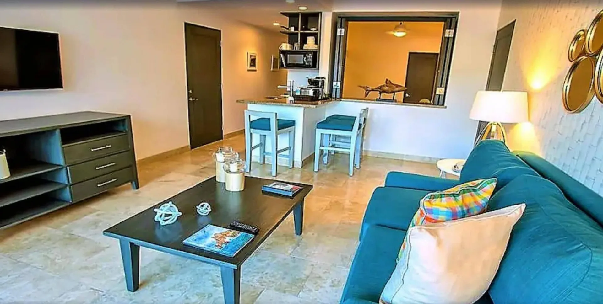 One Bedroom Deluxe living area with sofa, TV, and kitchenette at Corazón Cabo.