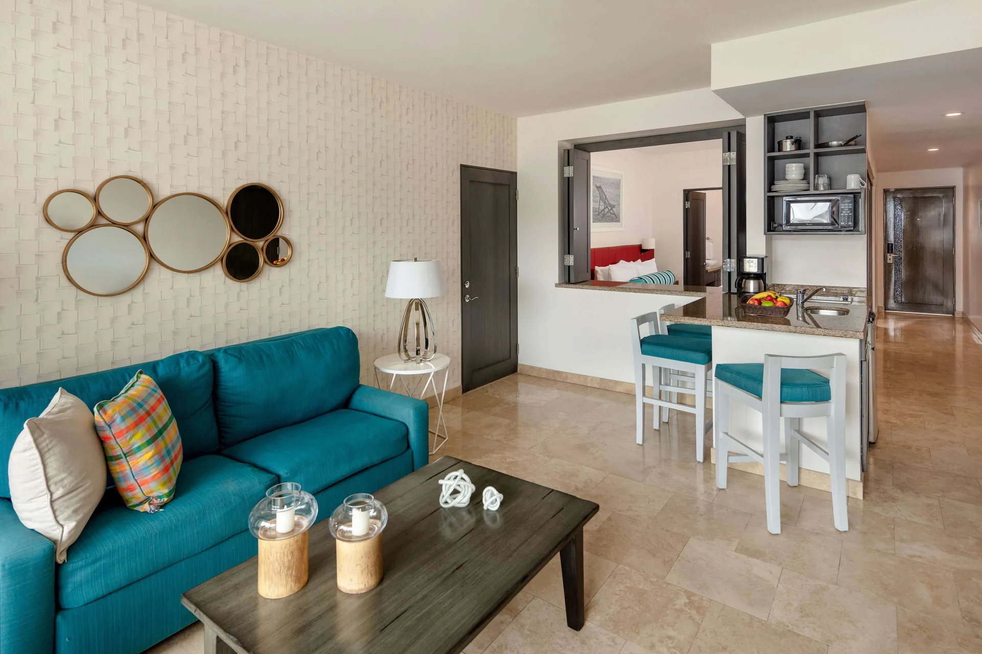 One Bedroom Deluxe living room with sofa, bar seating, and kitchenette at Corazón Cabo.