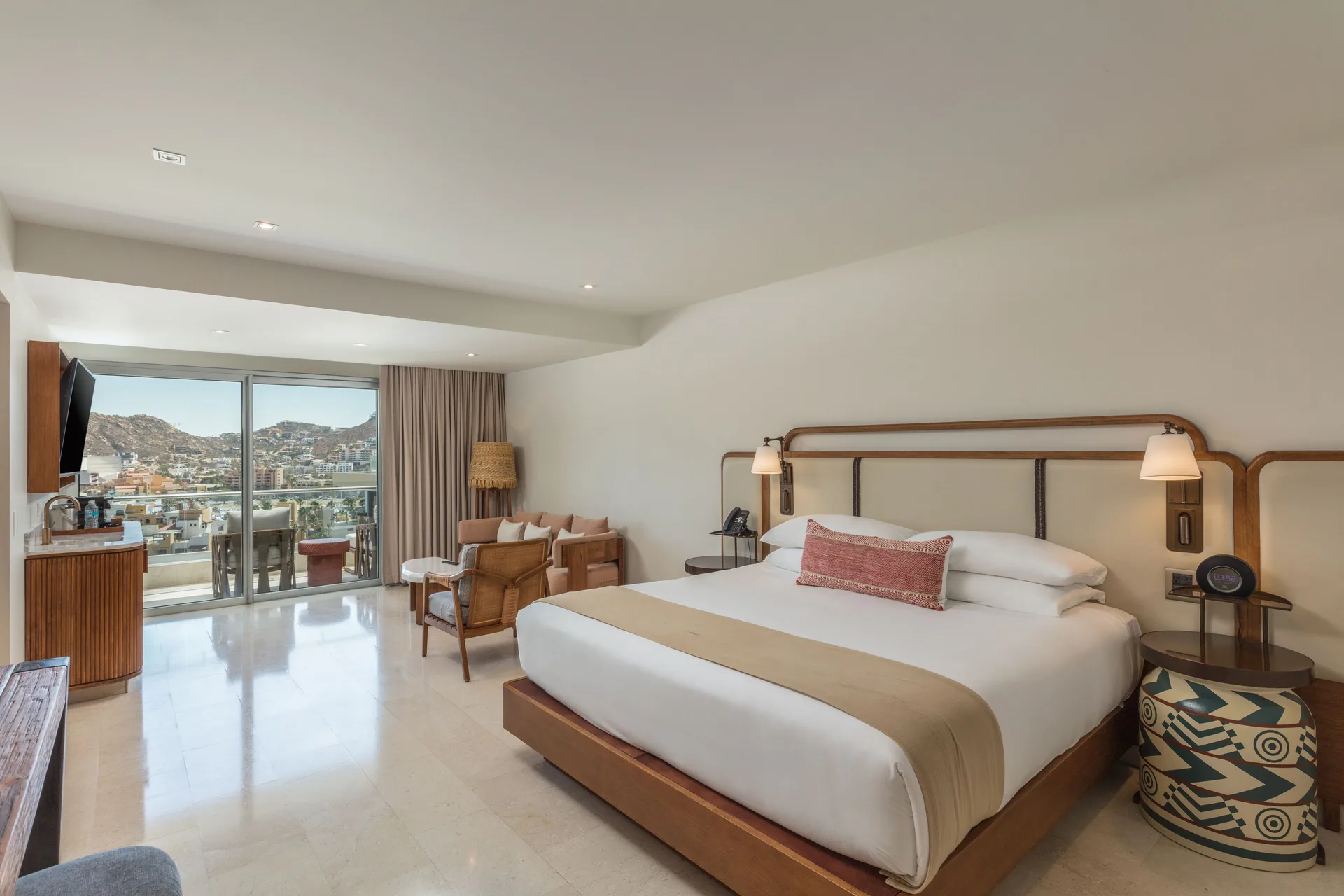 Infinity Sunset View room with king bed, lounge chairs, and balcony view at Corazón Cabo.