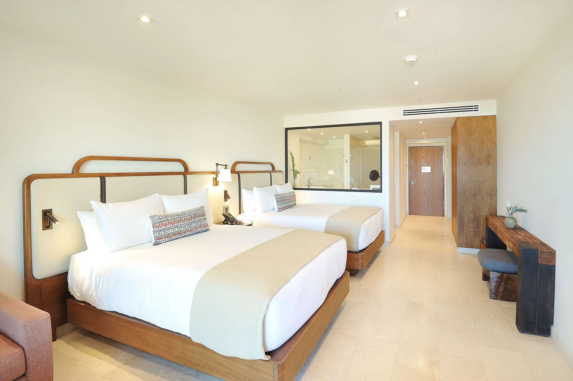 Infinity Sunset View room with two beds, desk, and glass bathroom wall at Corazón Cabo.