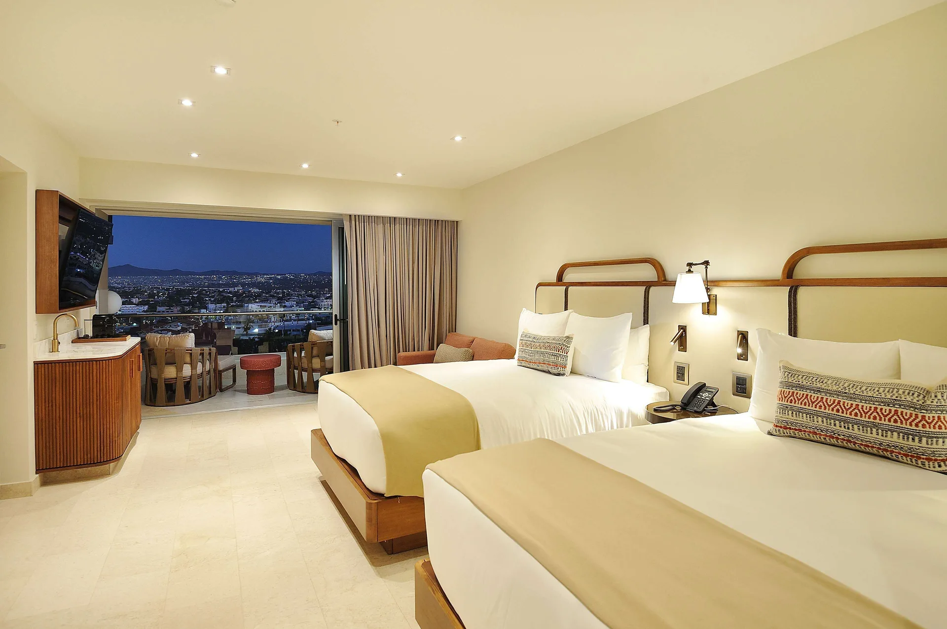 Infinity Sunset View room with two beds and nighttime balcony view at Corazón Cabo.