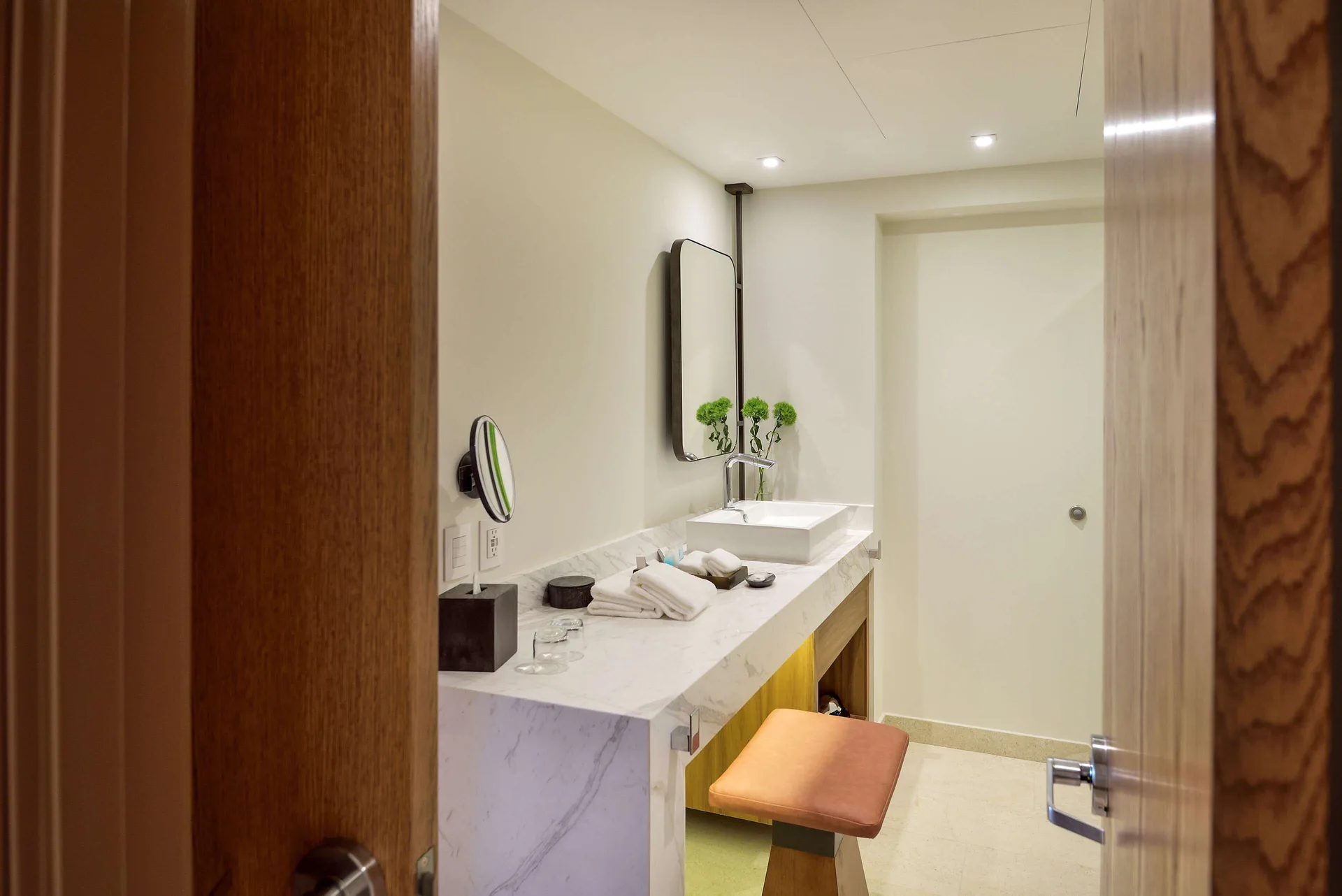 Bathroom vanity with vessel sink, mirror, towels, and stool in a suite at Corazón Cabo.