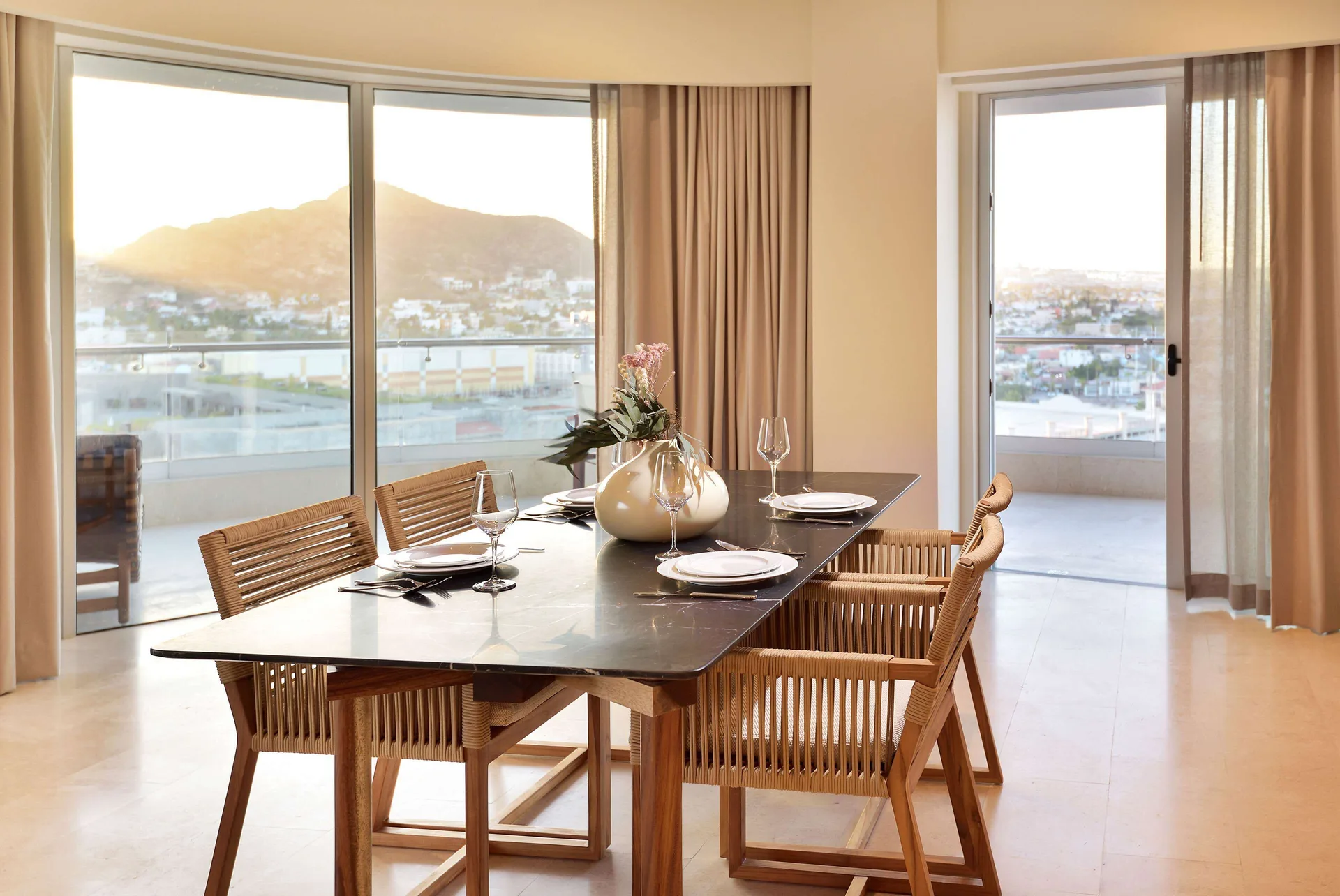 Dining table in a three-bedroom suite at Corazón Cabo with sunset hills and balcony views.