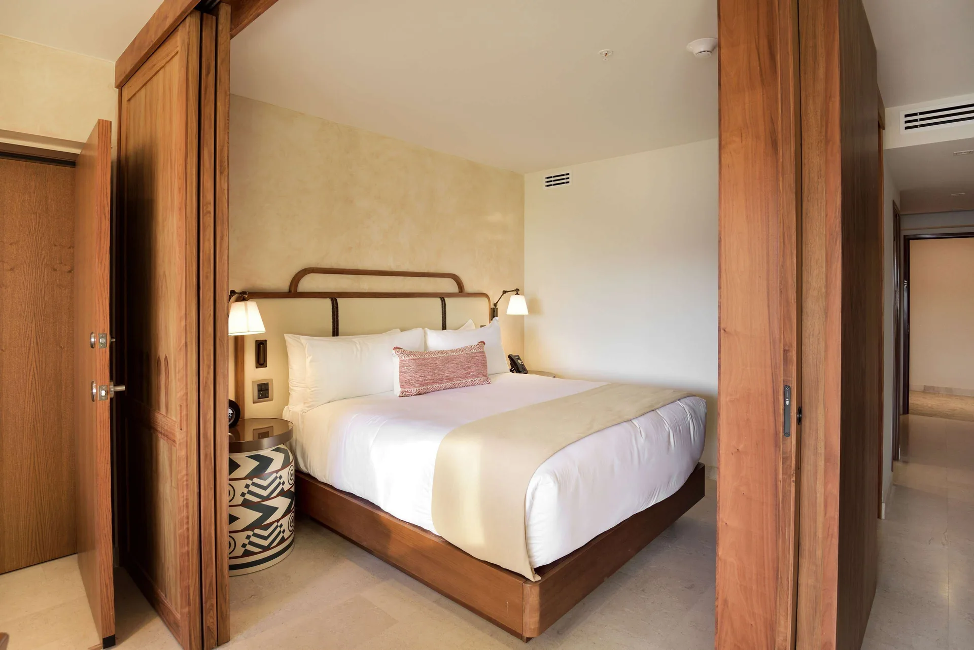 King bedroom framed by wood sliding doors in a three-bedroom suite at Corazón Cabo.