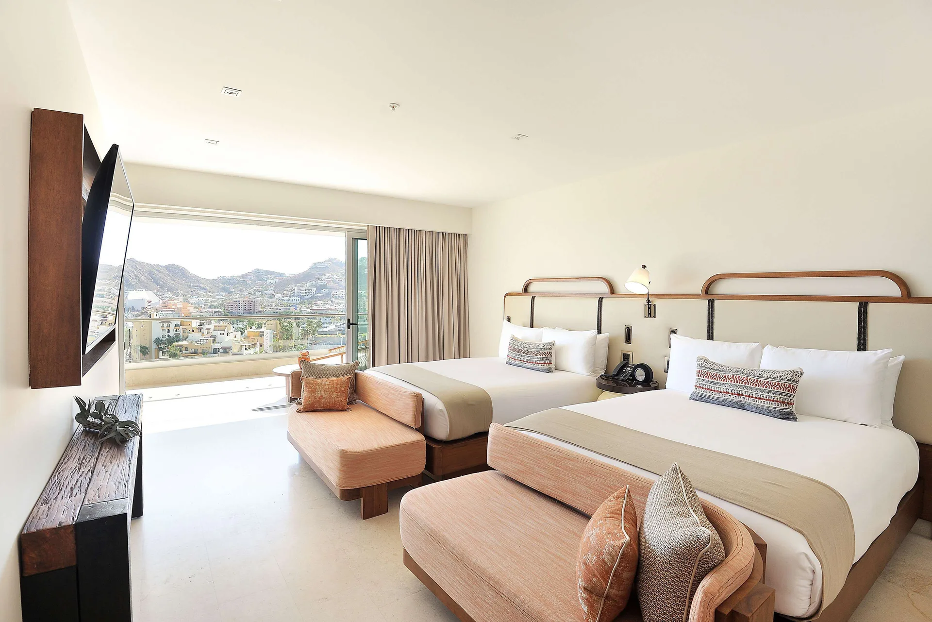 Three-bedroom suite bedroom with two queen beds and balcony view at Corazón Cabo.