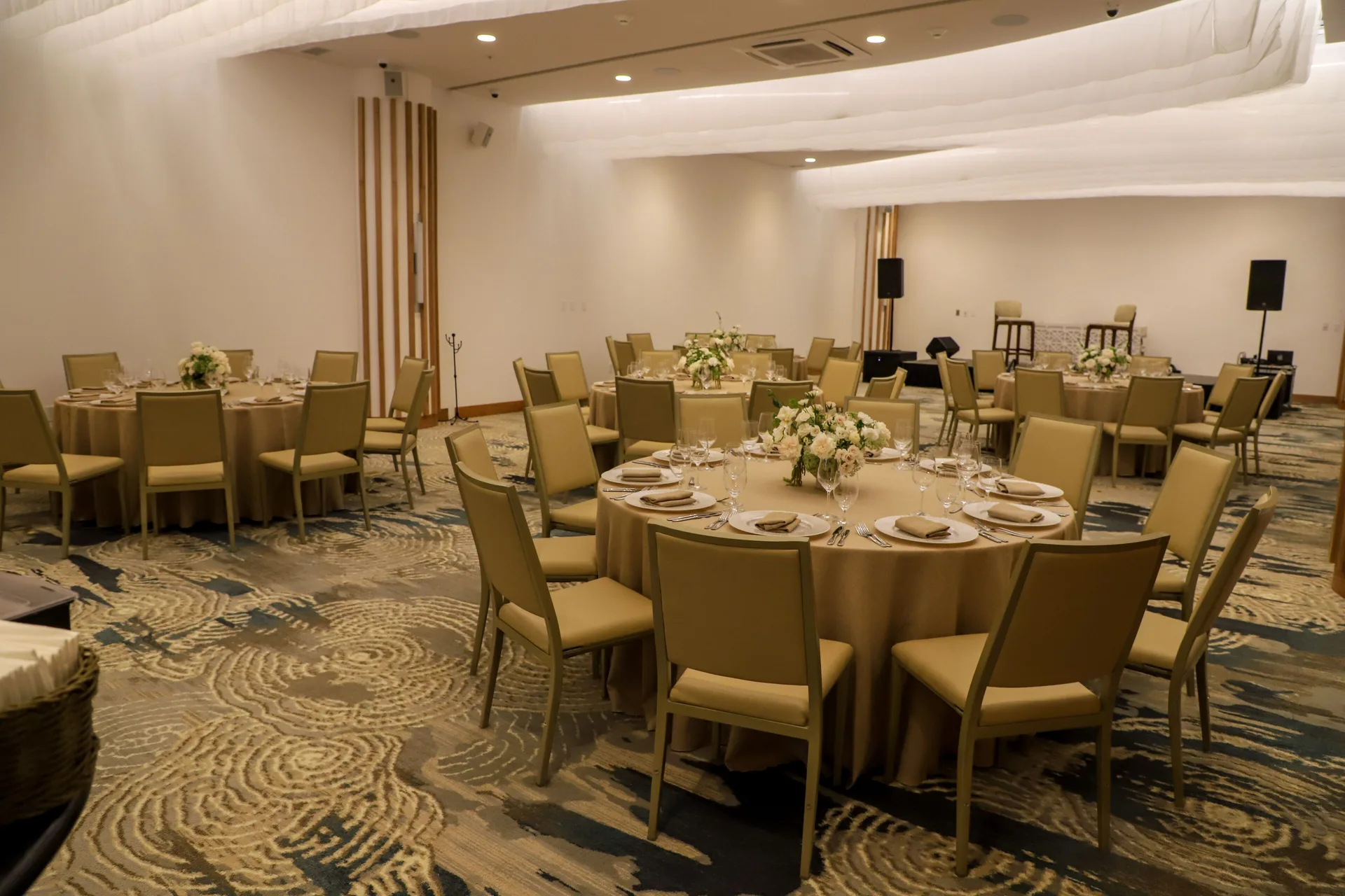 Banquet tables with white floral centerpieces in a ballroom at Corazón Cabo.