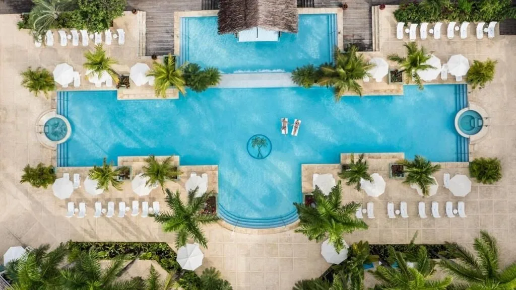 Aerial view of the main pool with loungers, umbrellas, and palms at Couples Negril.