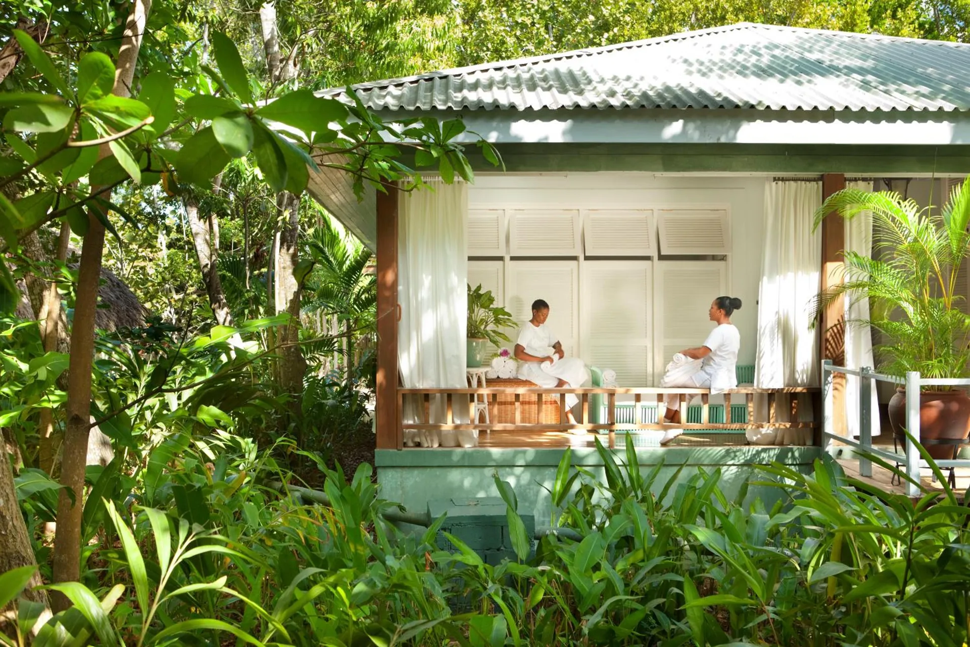 Guests in robes sitting on a shaded spa cottage porch at Couples Negril.