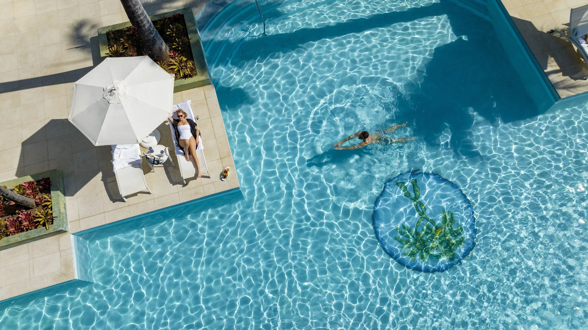 Overhead view of a swimmer and a sunbather beside the pool at Couples Negril.