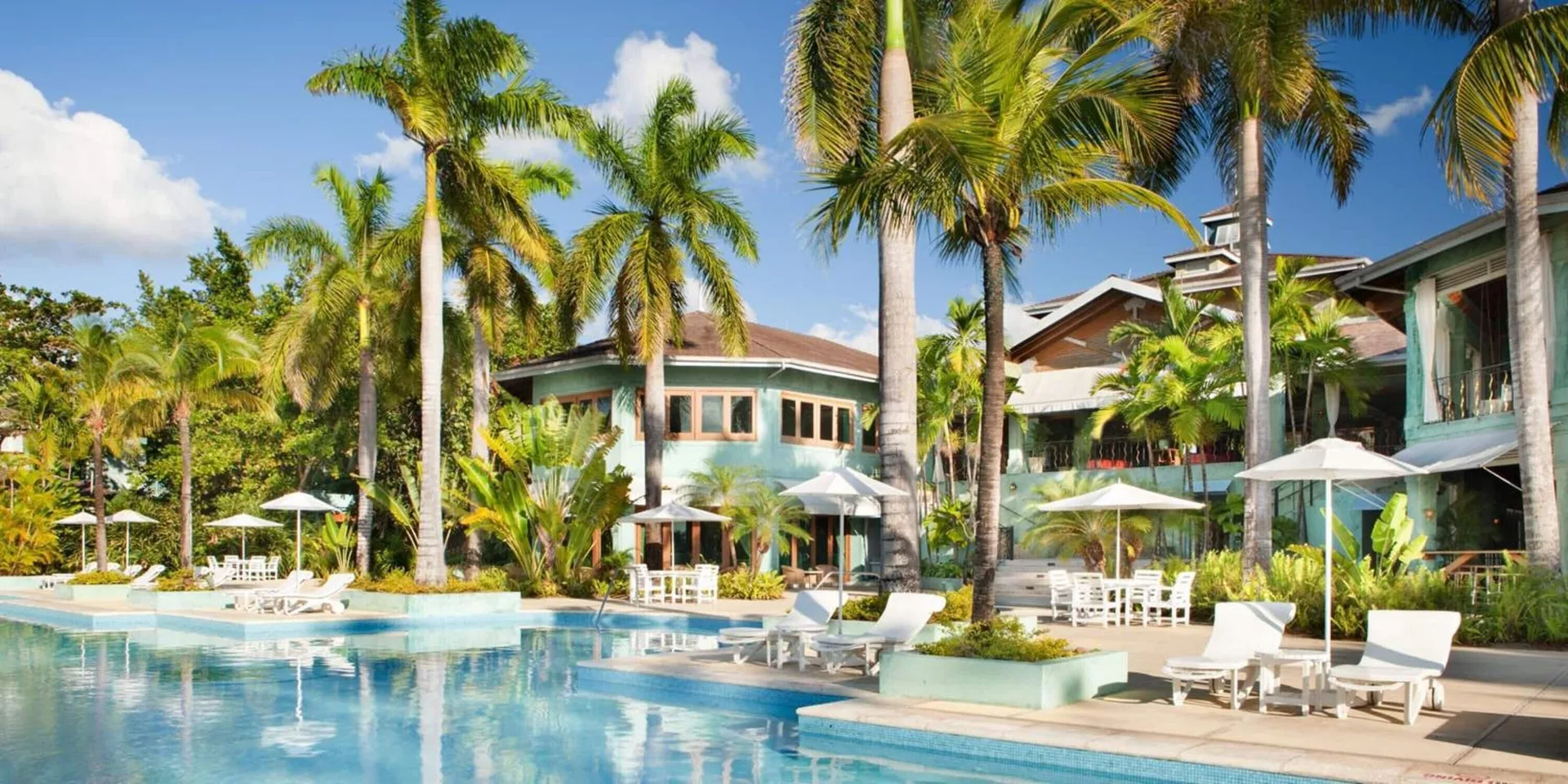 Palm-lined pool with loungers and resort buildings at Couples Negril.