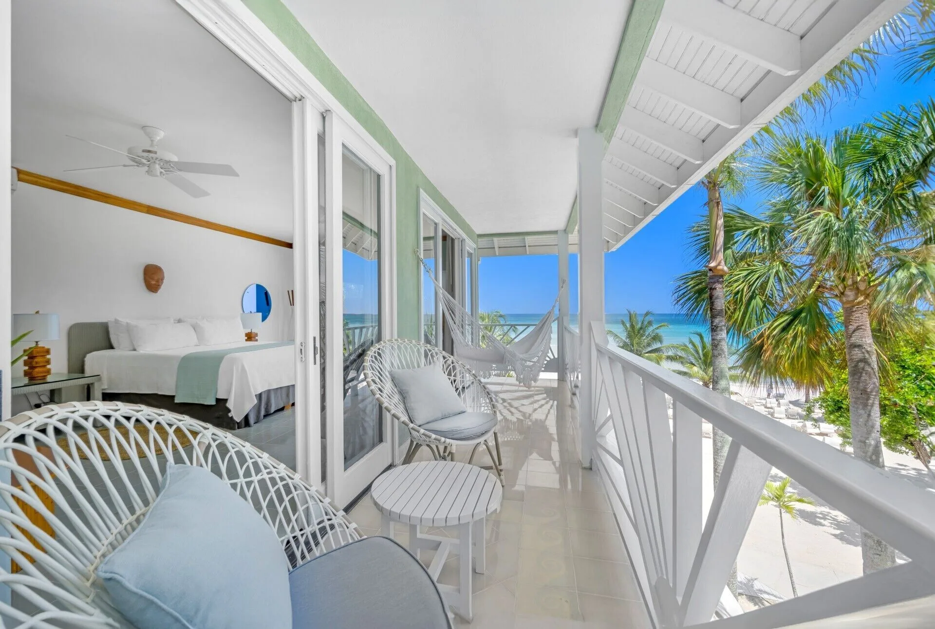 Beachfront Suite balcony with seating, hammock, ocean view, and bedroom doorway at Couples Negril.