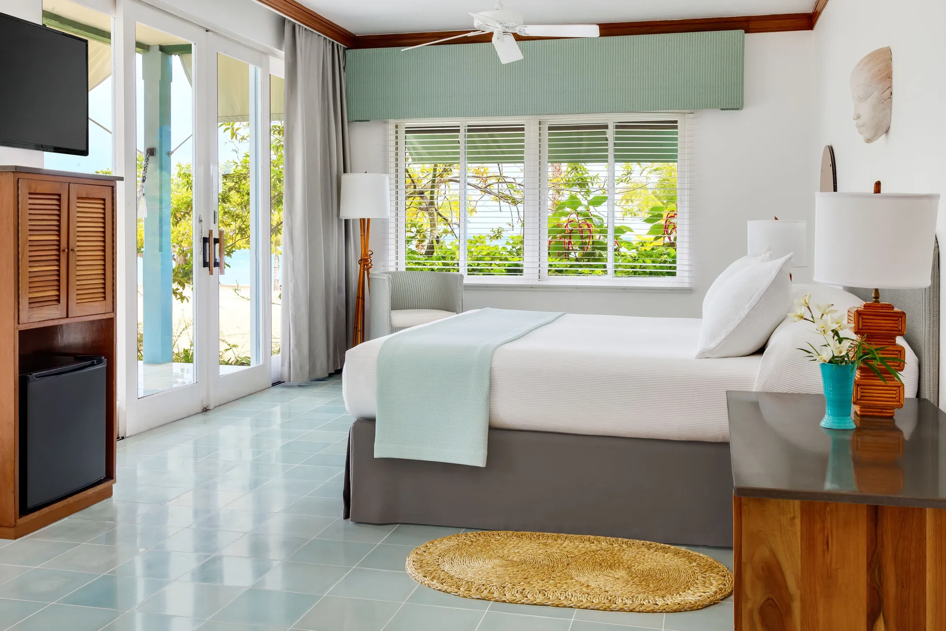 Beachfront Suite bedroom with king bed and garden-framed windows at Couples Negril.