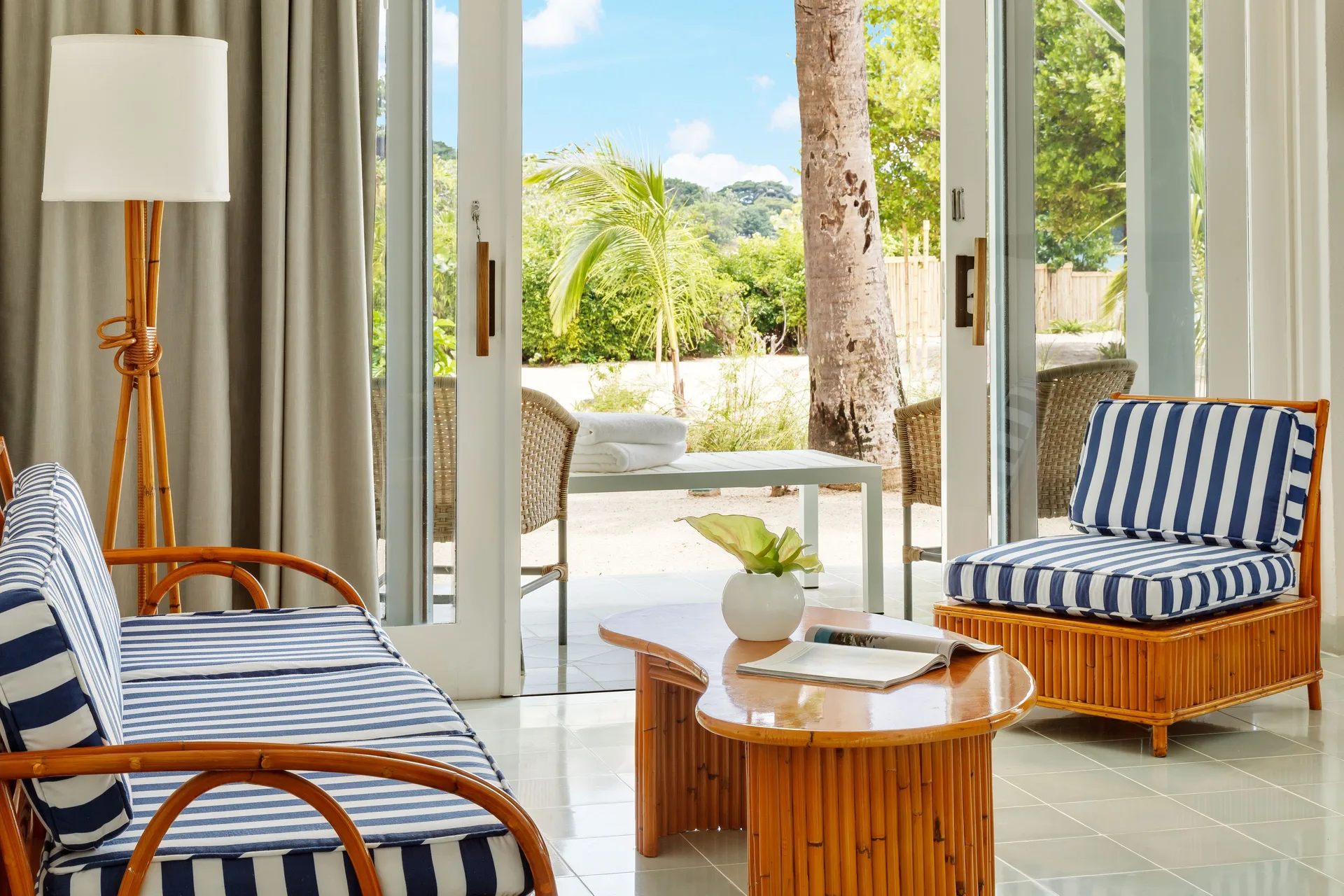 Beachfront Suite sitting area with striped cushions and open glass doors at Couples Negril.