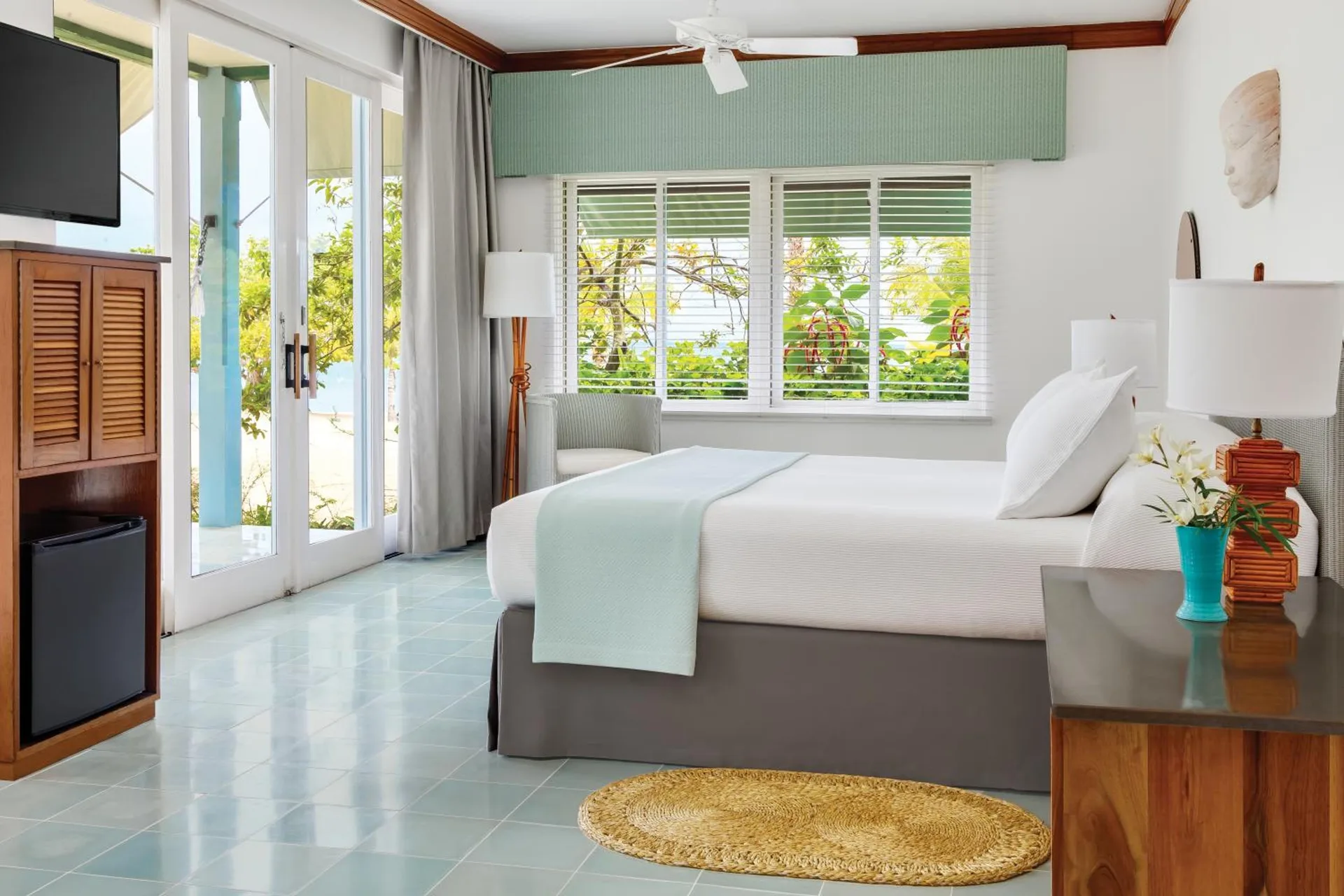 Deluxe Beachfront room with king bed, shuttered window, and balcony doors at Couples Negril.