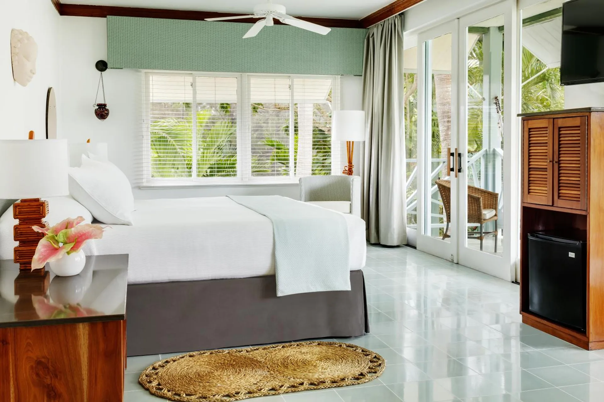 Garden Suite room with a white bed, louvered cabinet, and glass balcony doors at Couples Negril.